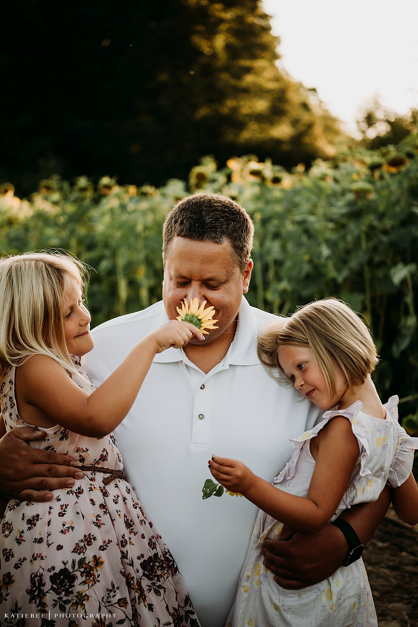 Candid family moment sharing laughter and sunflowers during golden hour photography session.