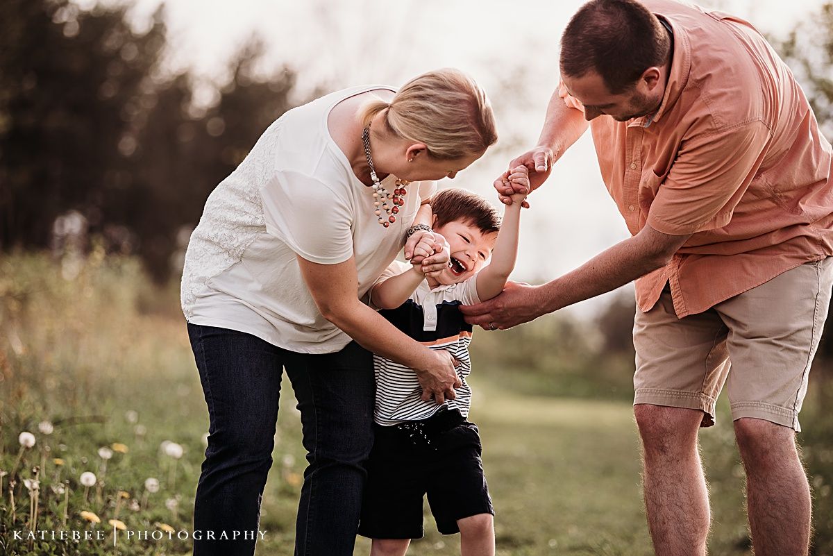 Playful family interaction in a sunlit meadow during golden hour.