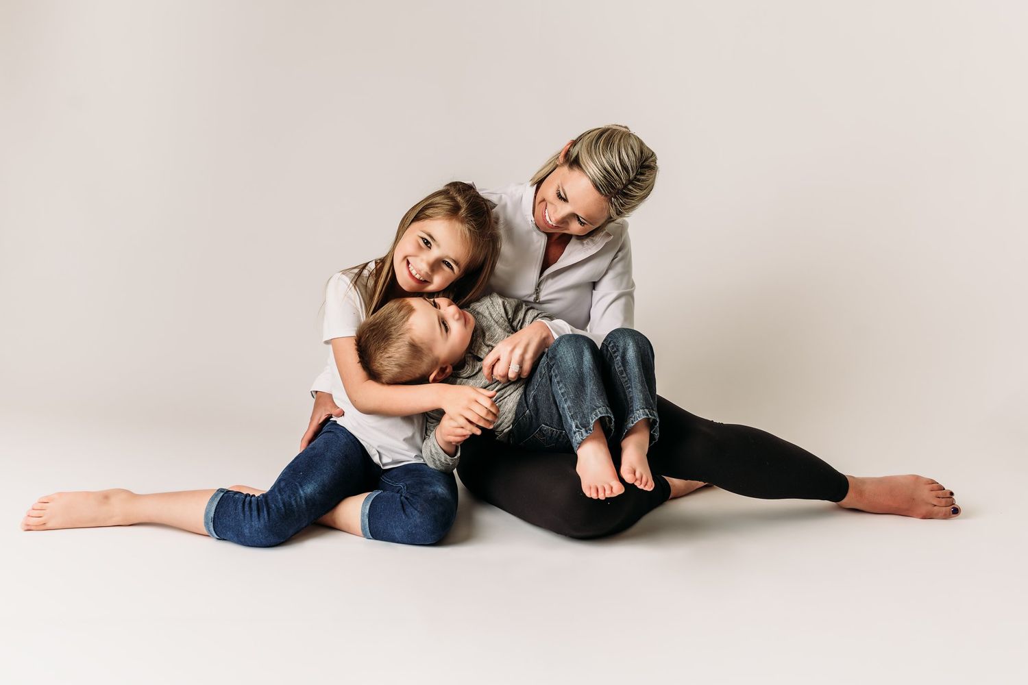 Candid family lifestyle portrait showing playful interaction on white studio background.