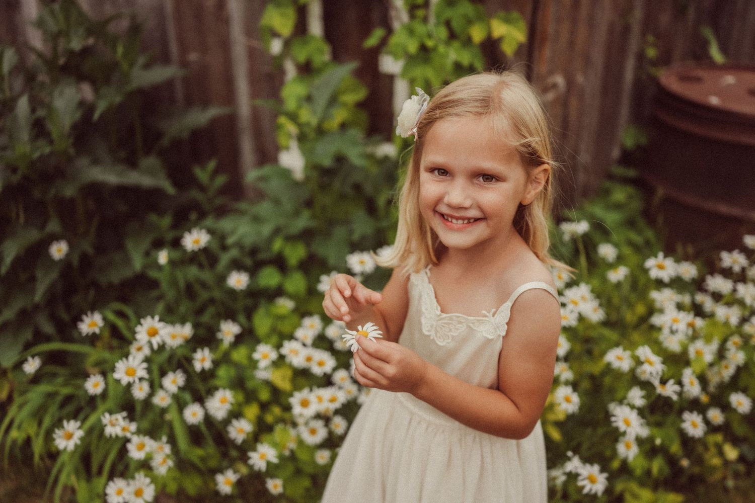Candid moment of joy among blooming daisies in garden setting.