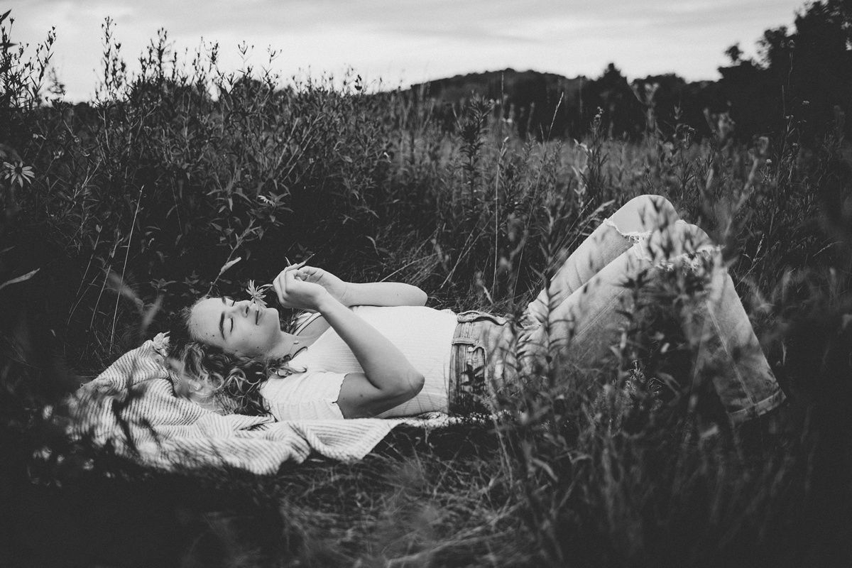 Black and white outdoor portrait of someone lying in tall grass.