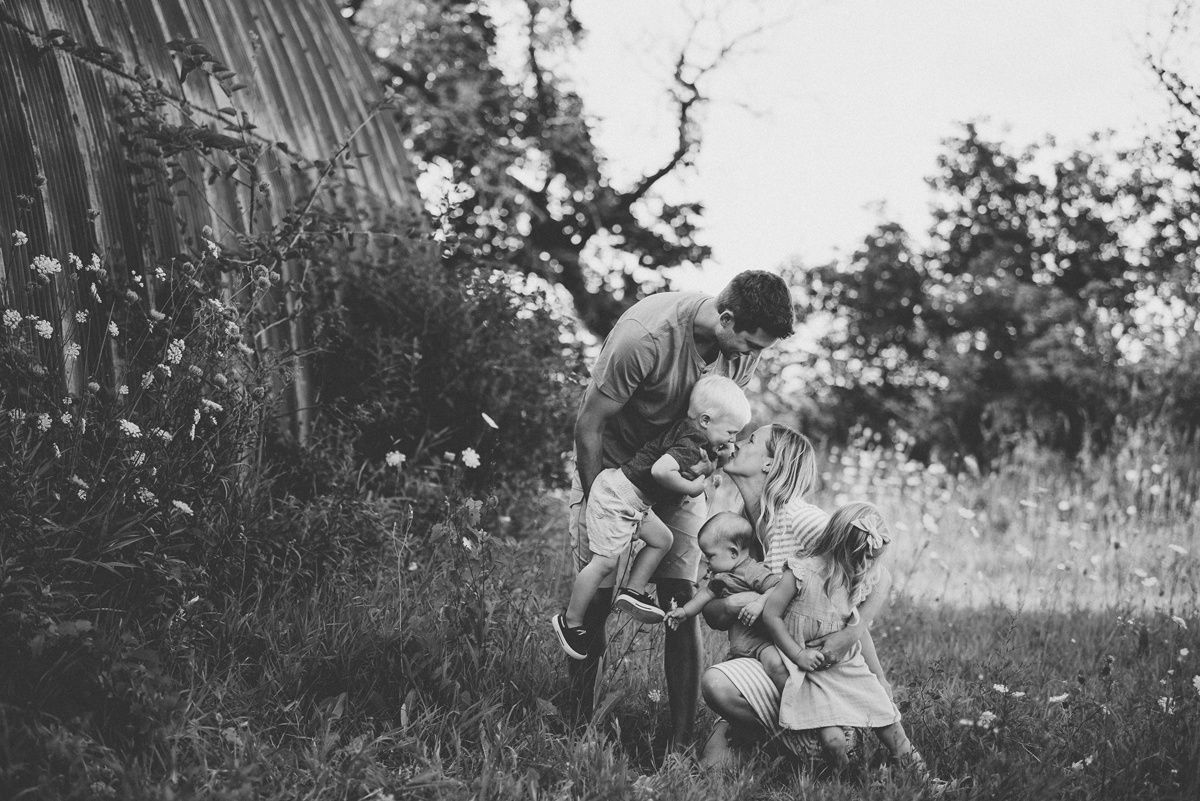 Black and white photo of a joyful outdoor family gathering in a rustic field setting.