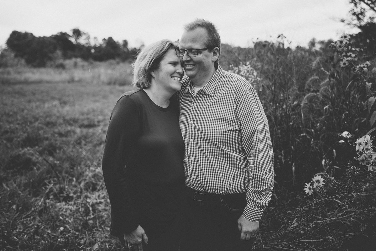 A black and white portrait of a couple sharing an intimate moment outdoors.