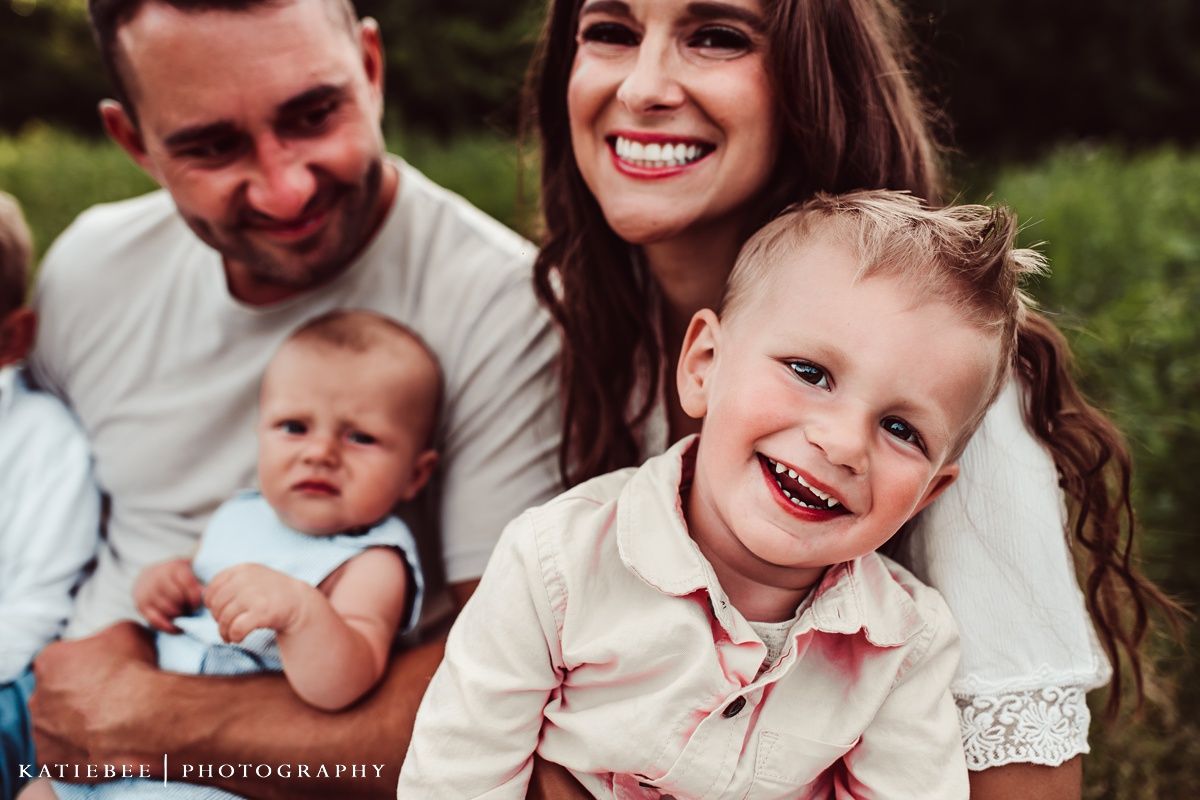 Casual outdoor family portrait with genuine smiles in natural lighting.