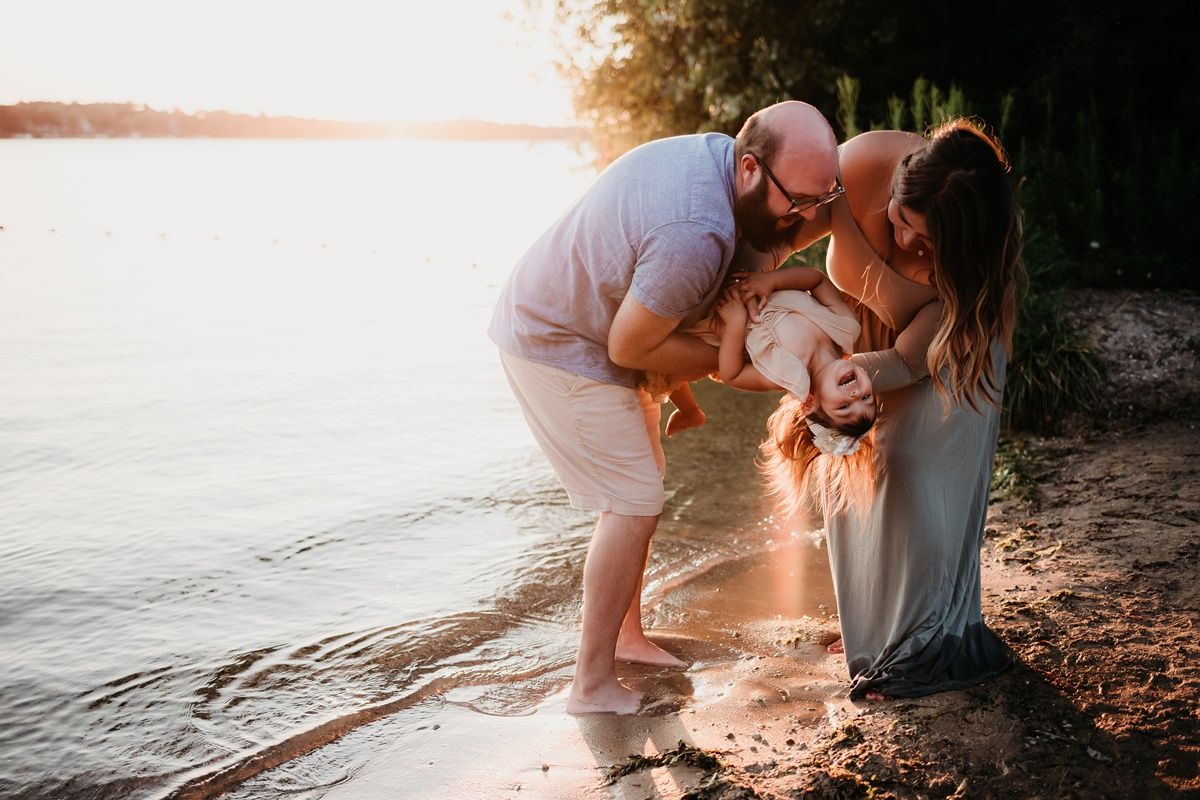 Family sharing an intimate moment together at the lake during golden hour sunset.