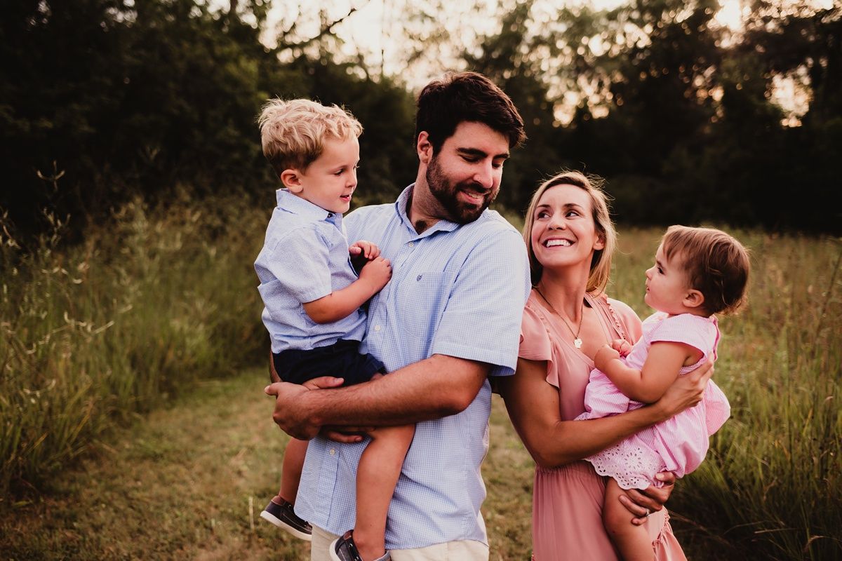 Family of four poses together during golden hour in matching casual outfits.