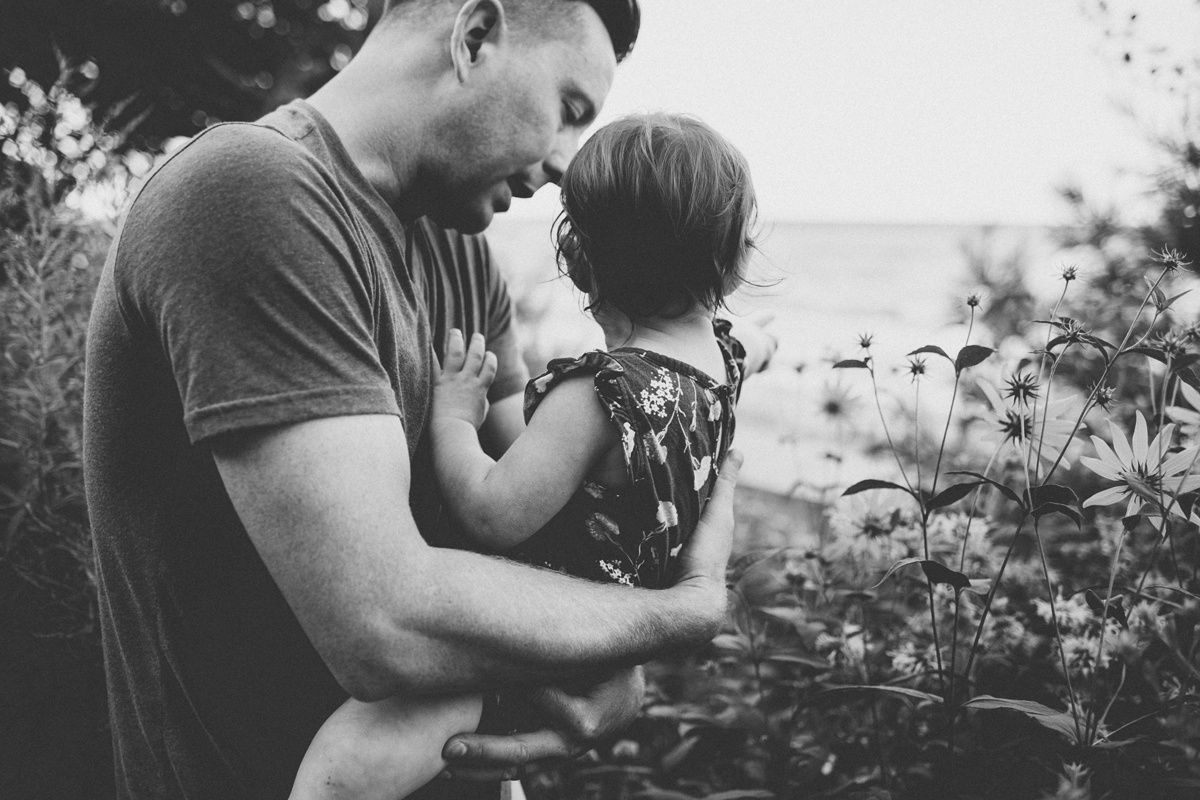 Black and white portrait of tender parenting moment among garden flowers.