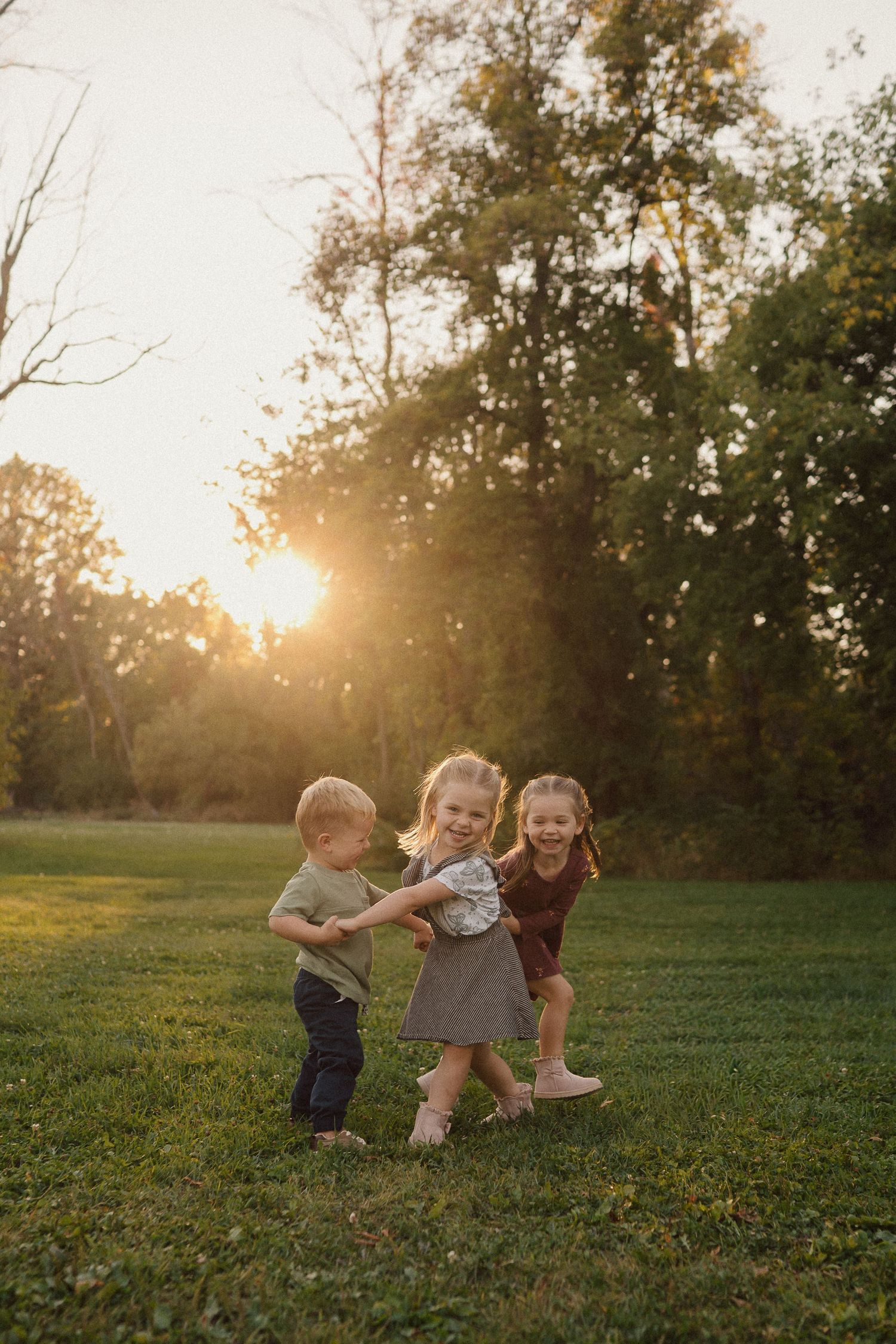 Family playing together in a grassy field during golden hour sunset.