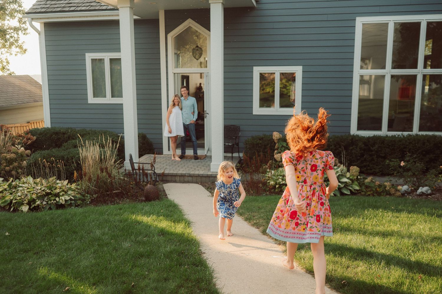 People walk along a path beside a green house on a sunny summer day.