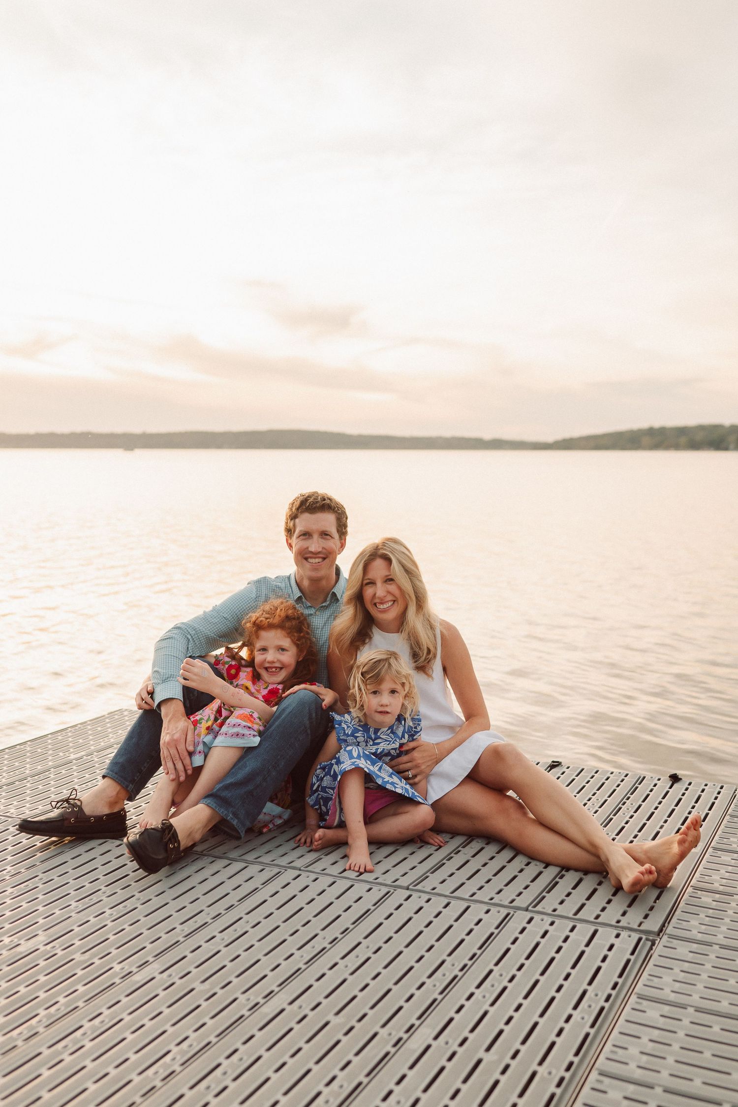 A group relaxes together on a wooden dock by the water during sunset.