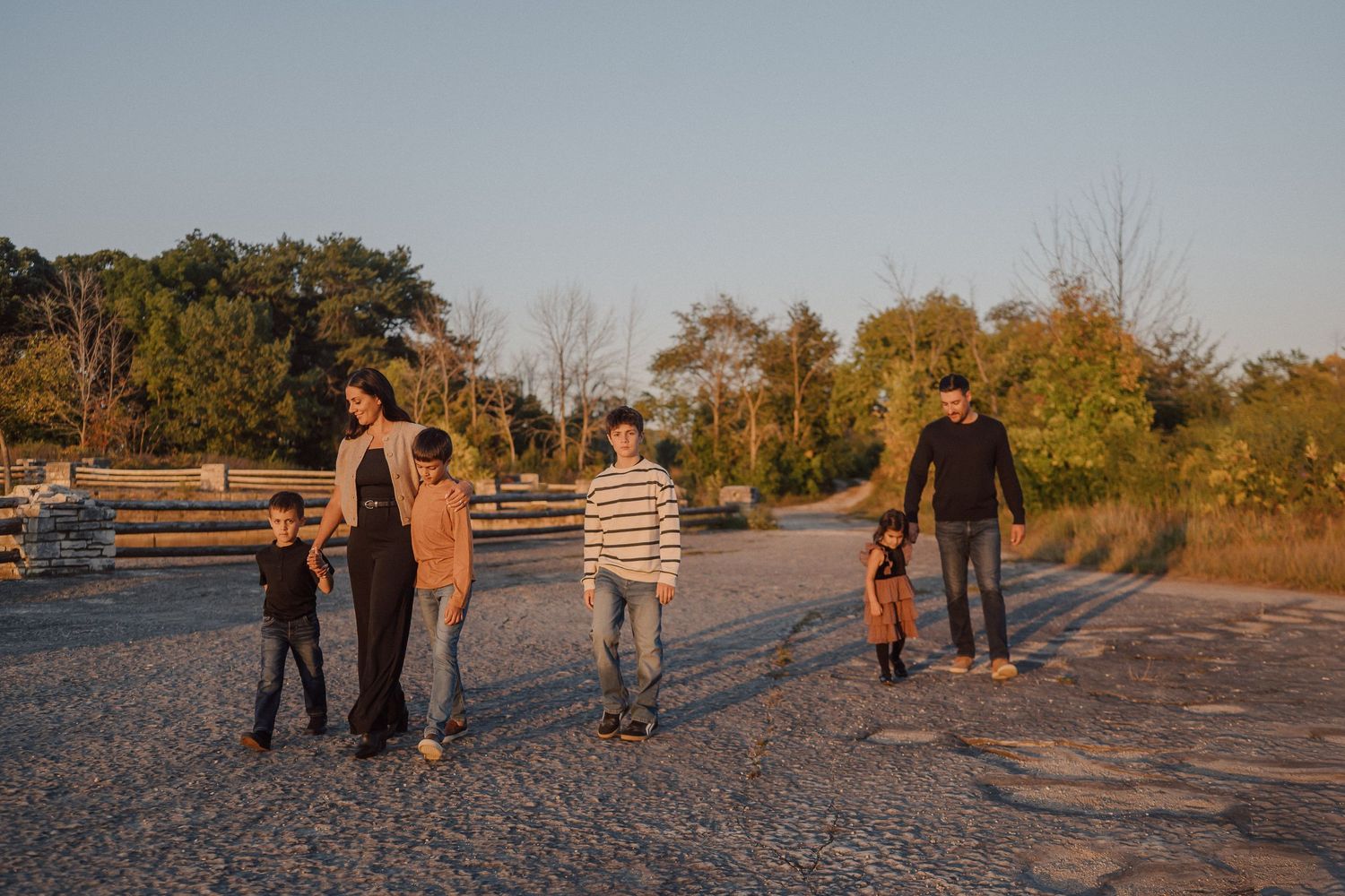 A series of sunset silhouettes of people walking along a beach path during golden hour.