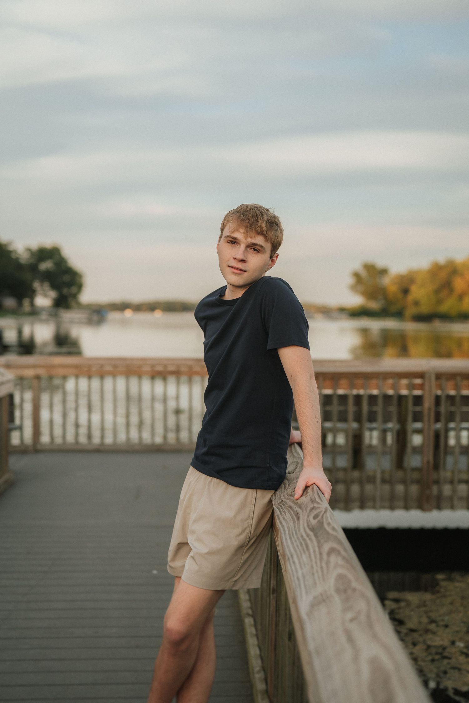 Lifestyle portraits on a wooden boardwalk by the water during golden hour with casual attire.