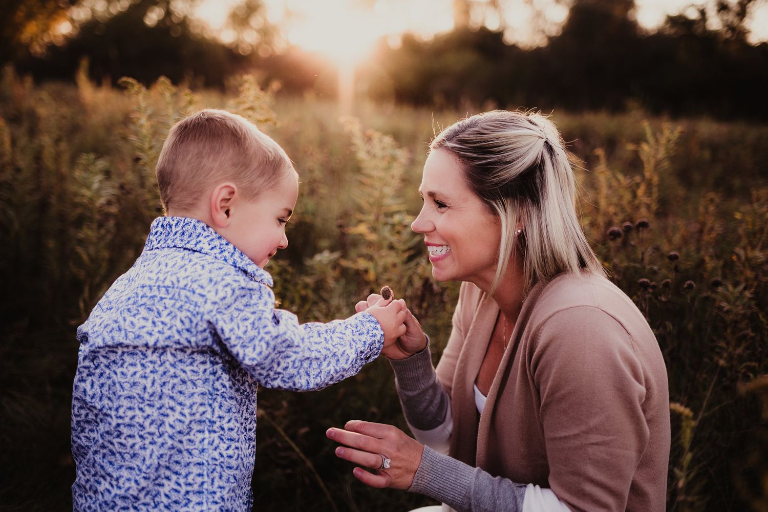 Joyful outdoor moment between adult and child holding hands in tall grass.