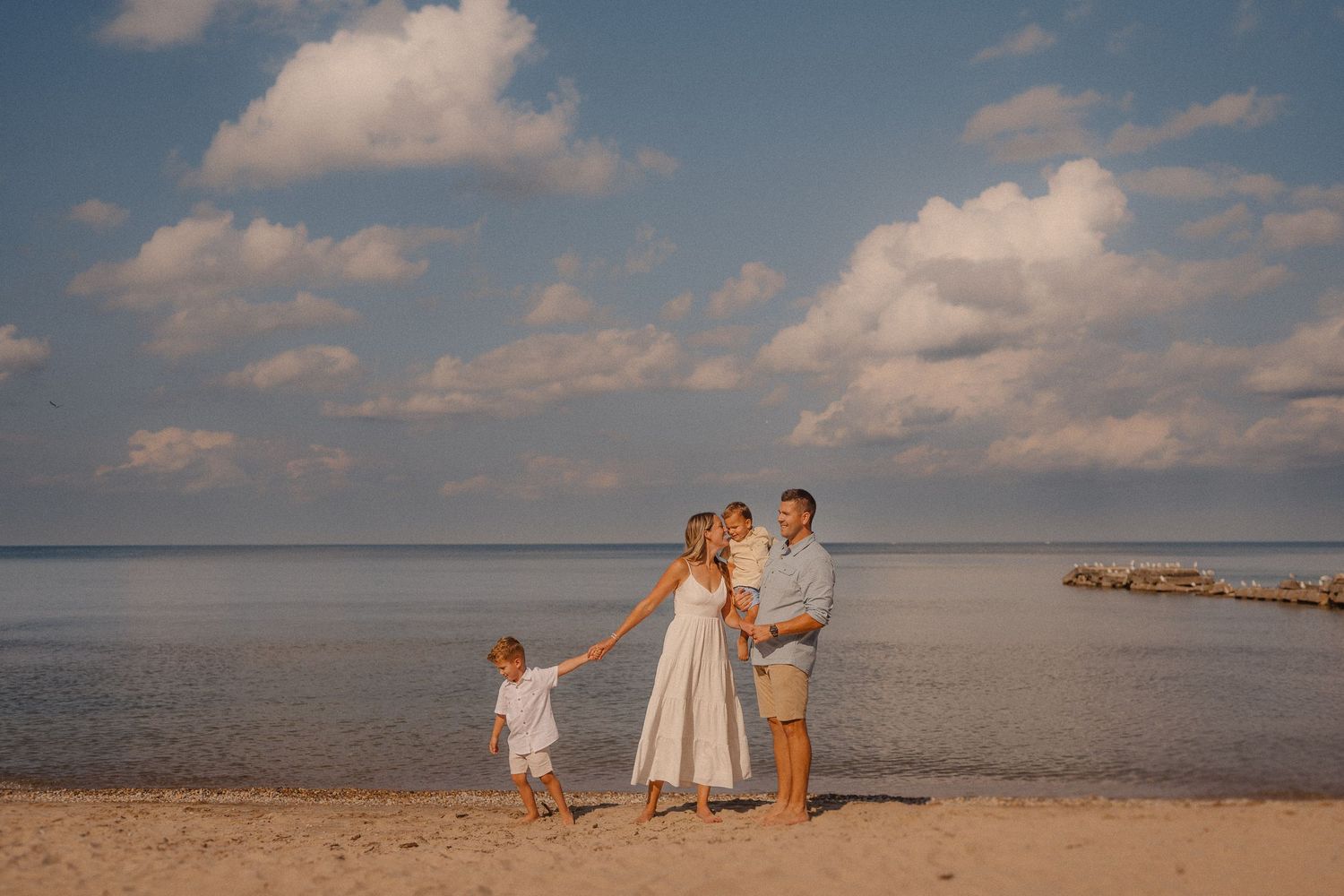 A family standing together on a peaceful beach at sunset.