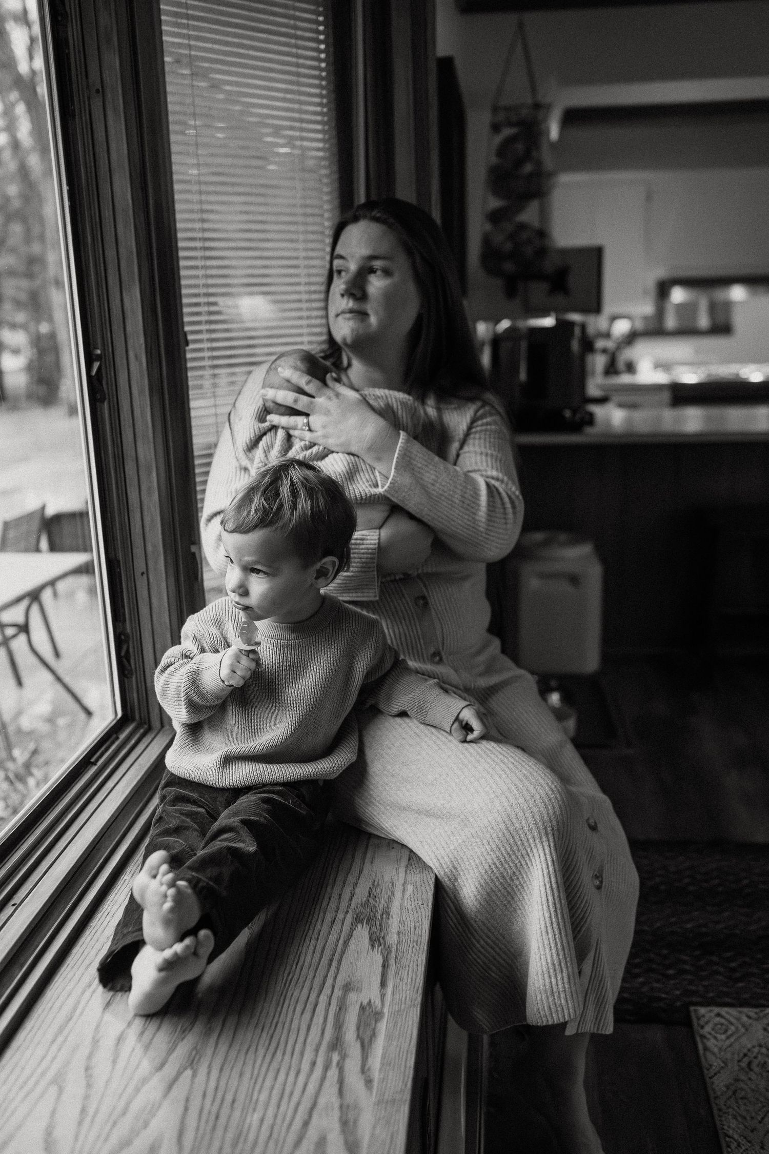 Family sitting by window in natural light sharing intimate moments together.