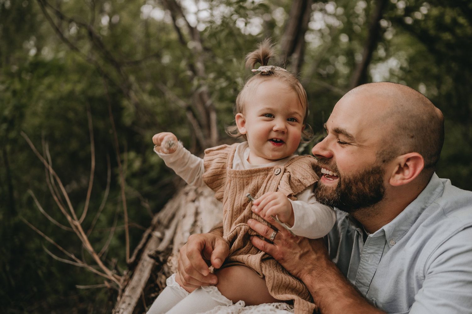 A joyful candid moment between parent and child sitting outdoors.