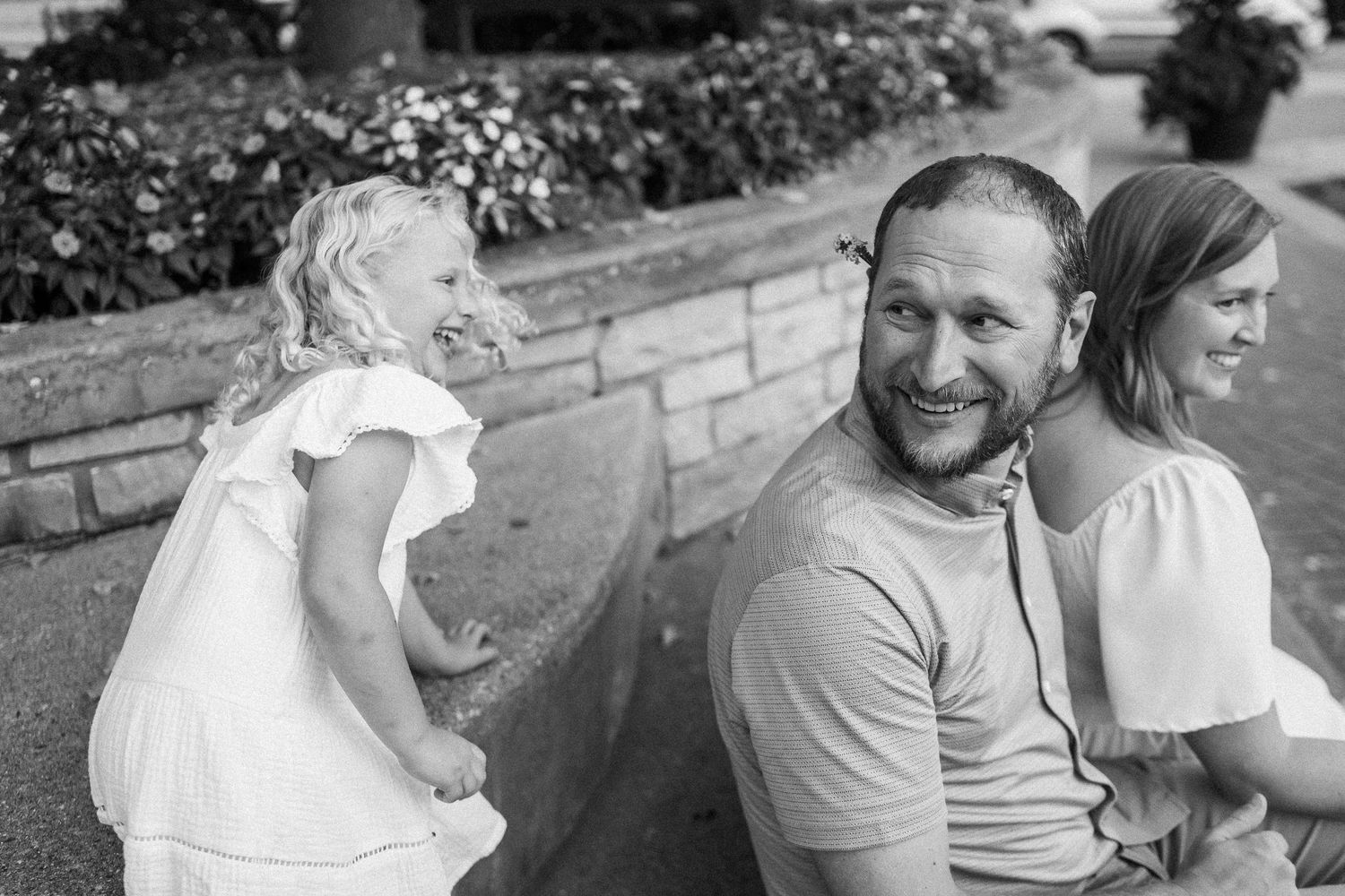 A series of candid black and white photos showing joyful moments and laughter between people outdoors.