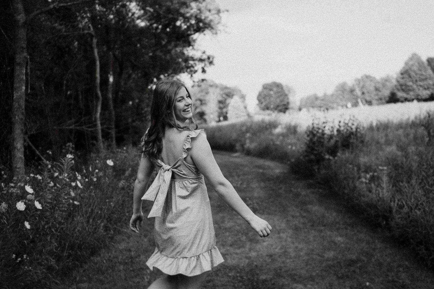 Black and white portrait of dancing movement on a country path with flowing dress.