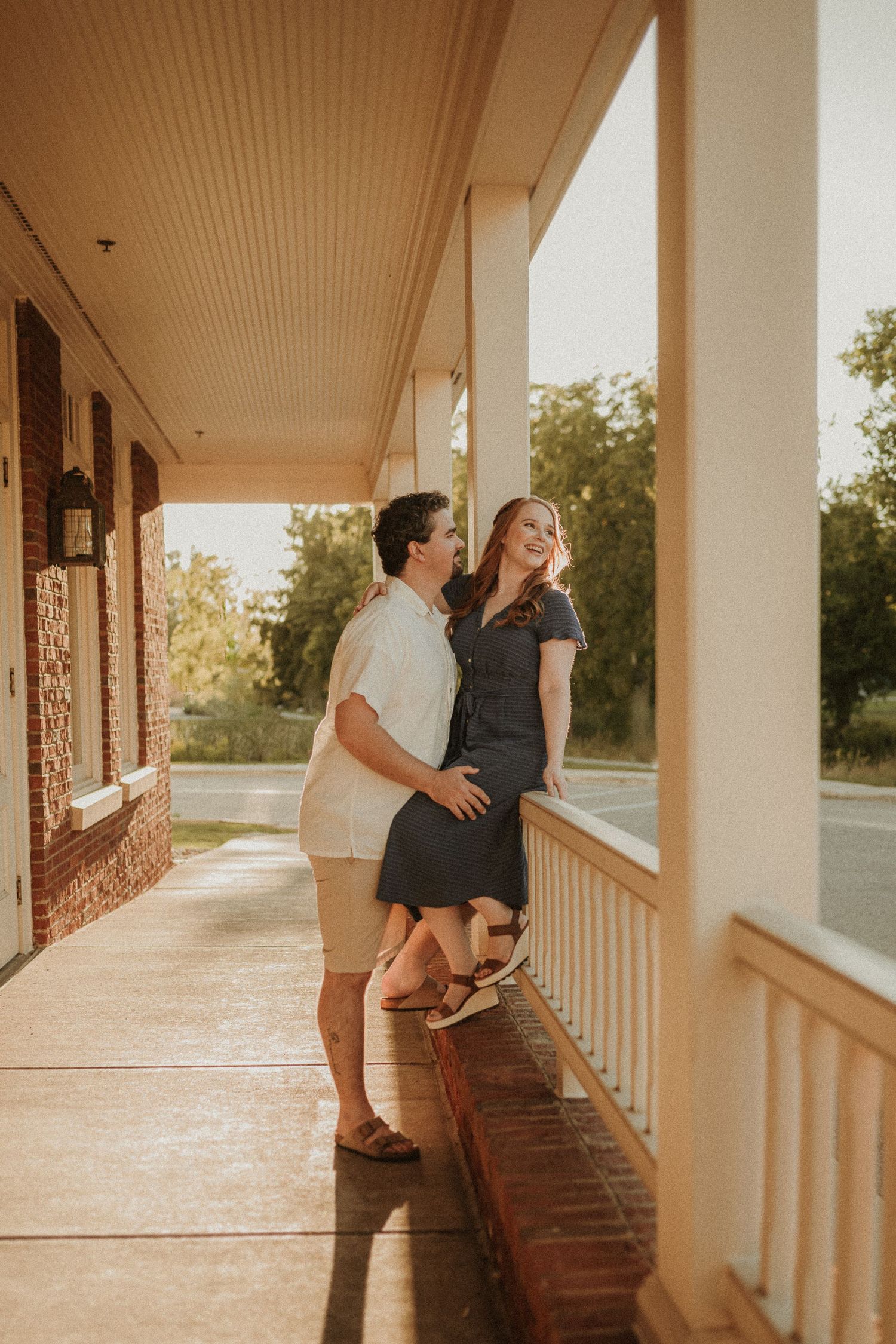 Couple sharing a playful moment on a covered porch at sunset.