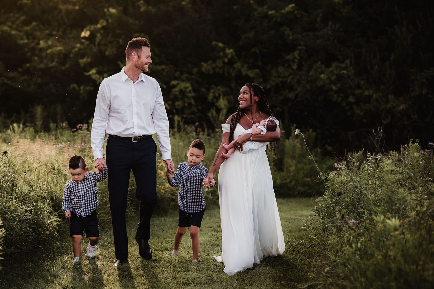 A sunset family portrait in a meadow with tall grass and golden light.