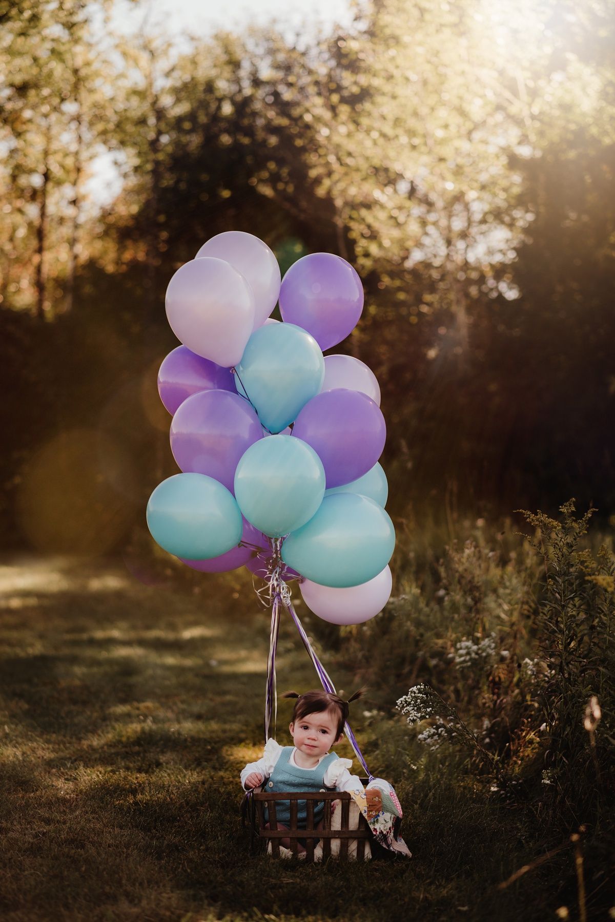 Dreamy outdoor photo with purple and blue balloons at golden hour.