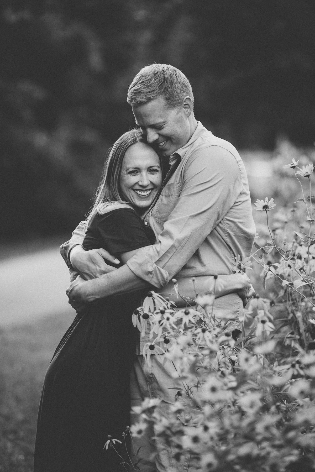 Black and white portrait of couple sharing intimate moment in garden setting.