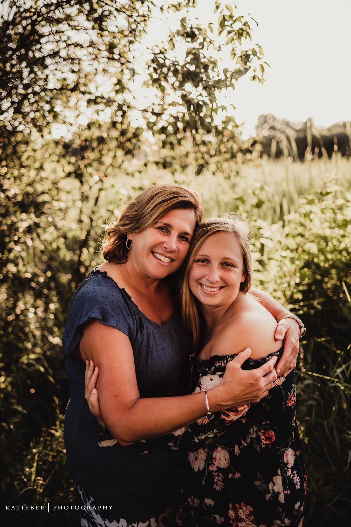 Two people embracing and smiling during a sunset photo session outdoors.
