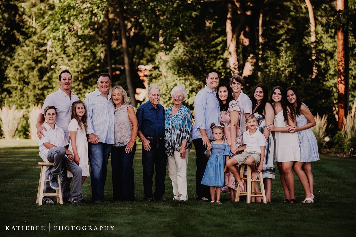 Large family portrait of multiple generations posed together outdoors in coordinated white and blue outfits.