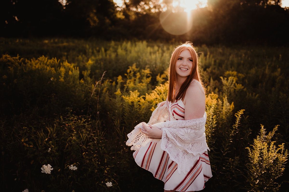 A golden hour outdoor portrait featuring a striped dress and lace cardigan.