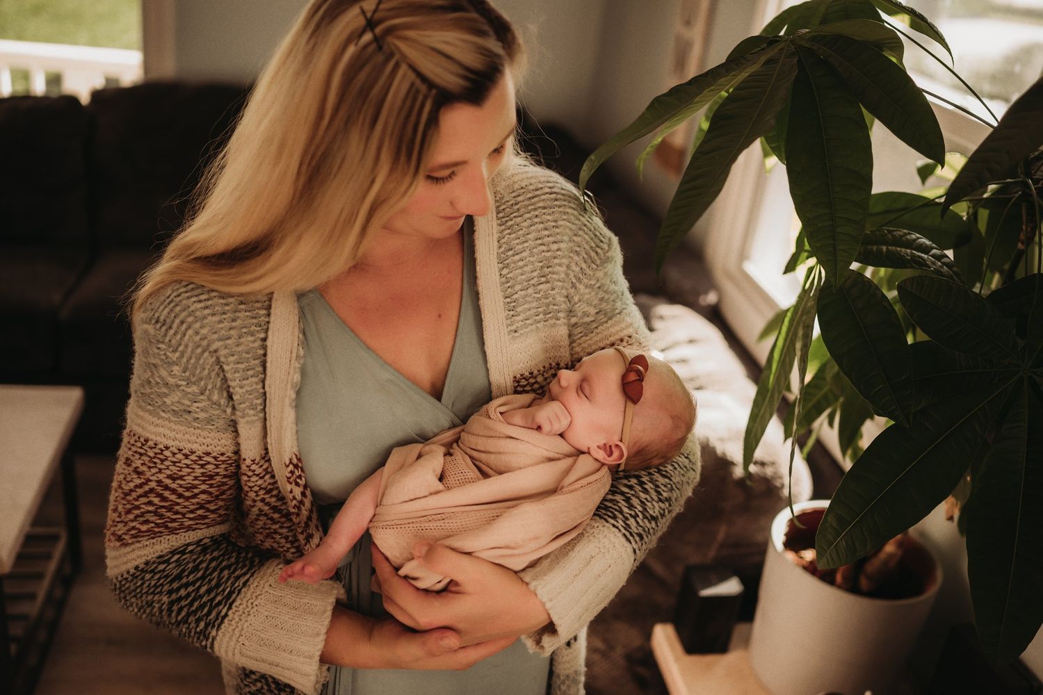 A tender moment captured of mother and baby during a feeding session near a houseplant.