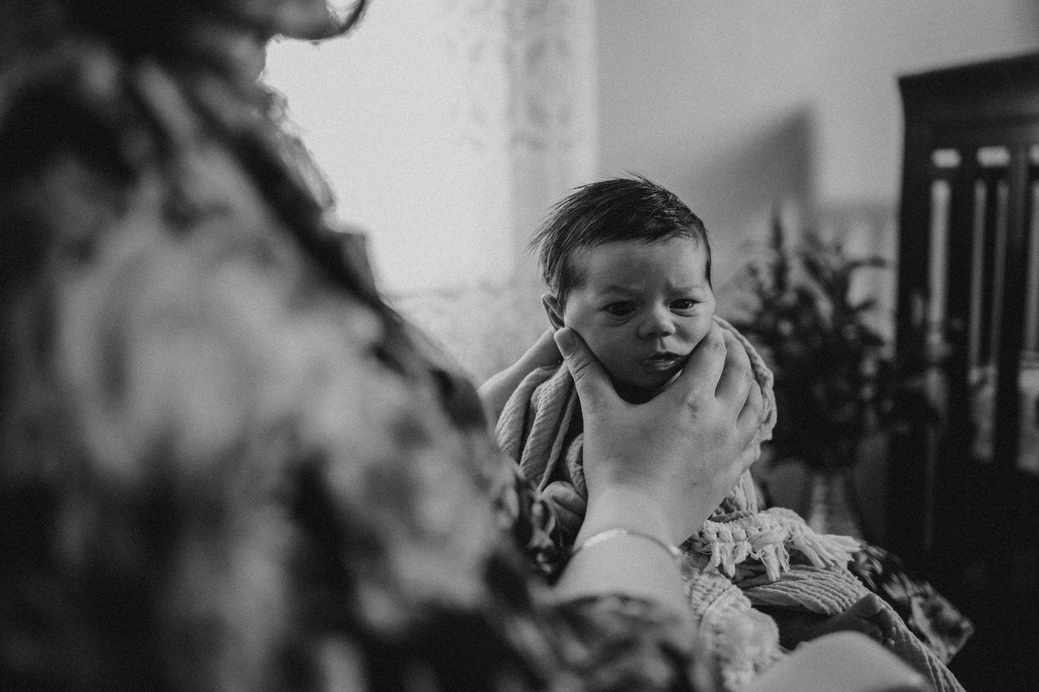 Black and white intimate newborn photography in nursery setting.
