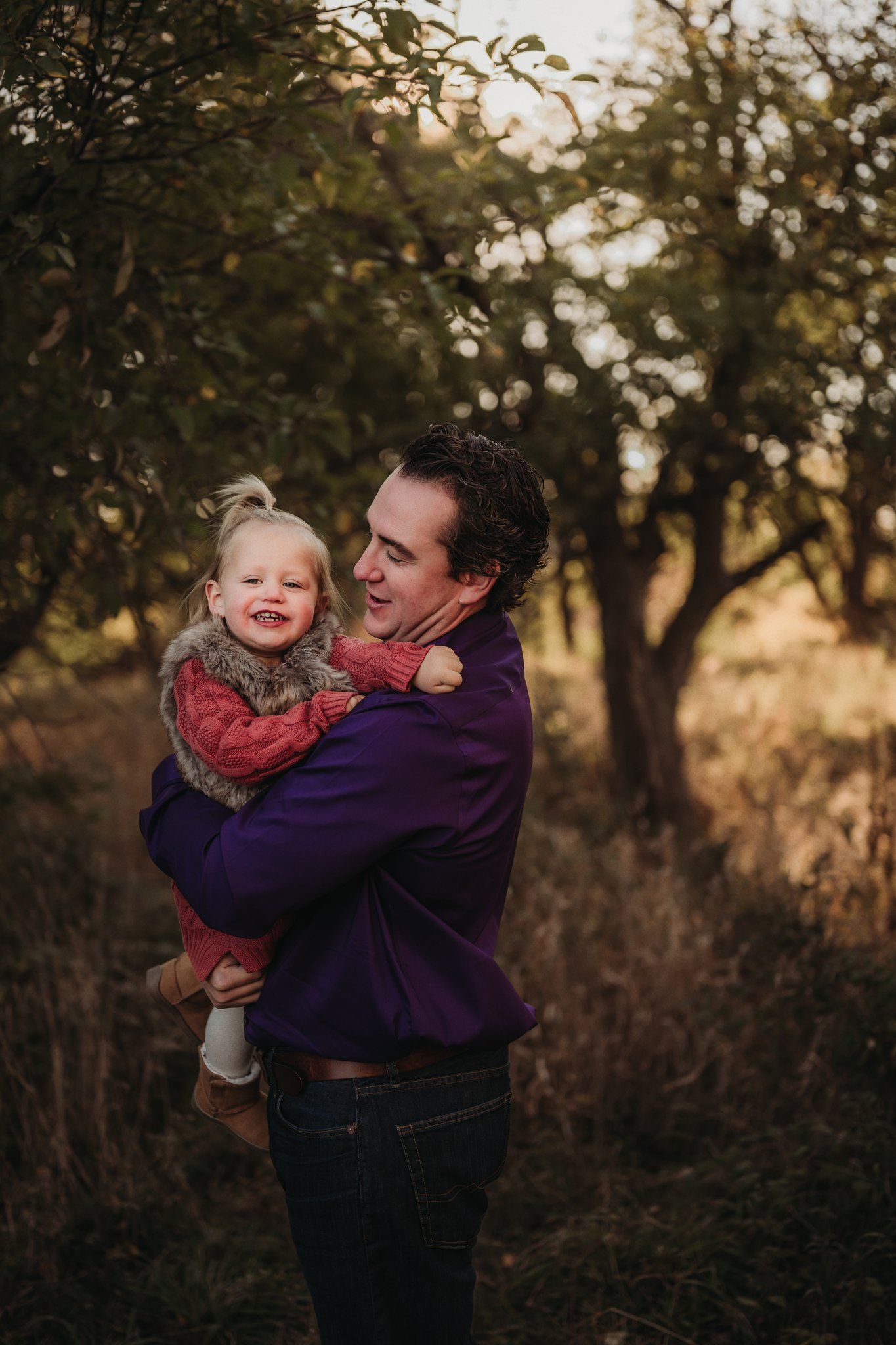 Joyful outdoor portrait with purple sweater against autumn foliage.