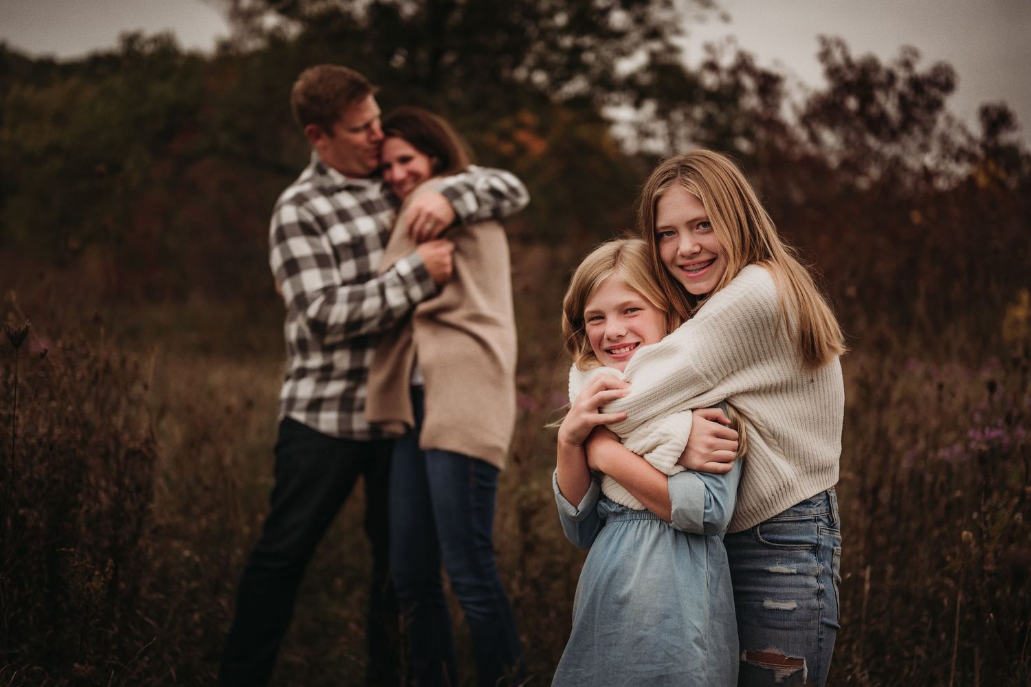 Family in sweaters embraces outdoors during fall season.