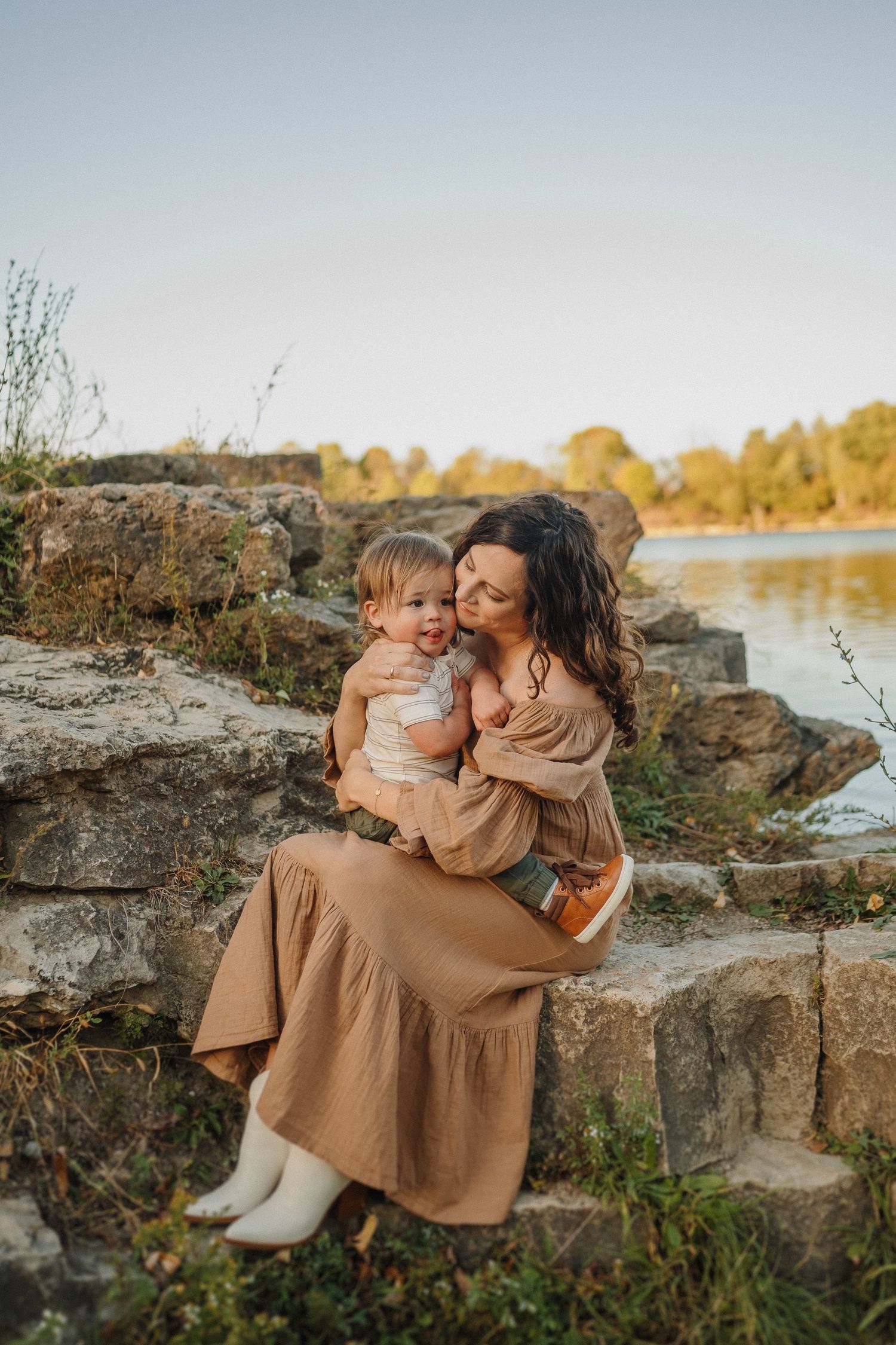 A heartwarming embrace shared on rocky steps overlooking a serene lake at sunset.