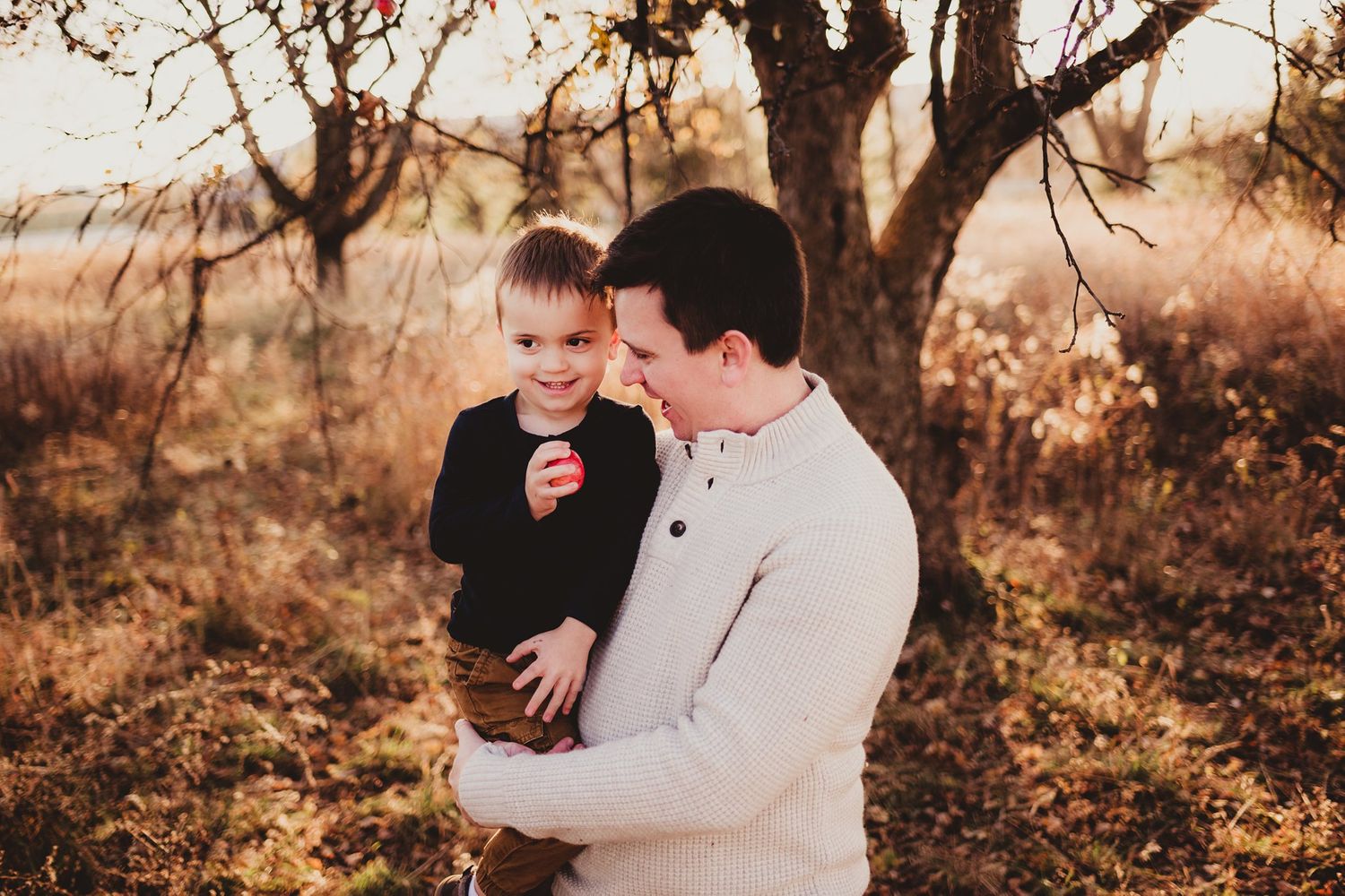 Intimate portrait of parent and child against autumn foliage.