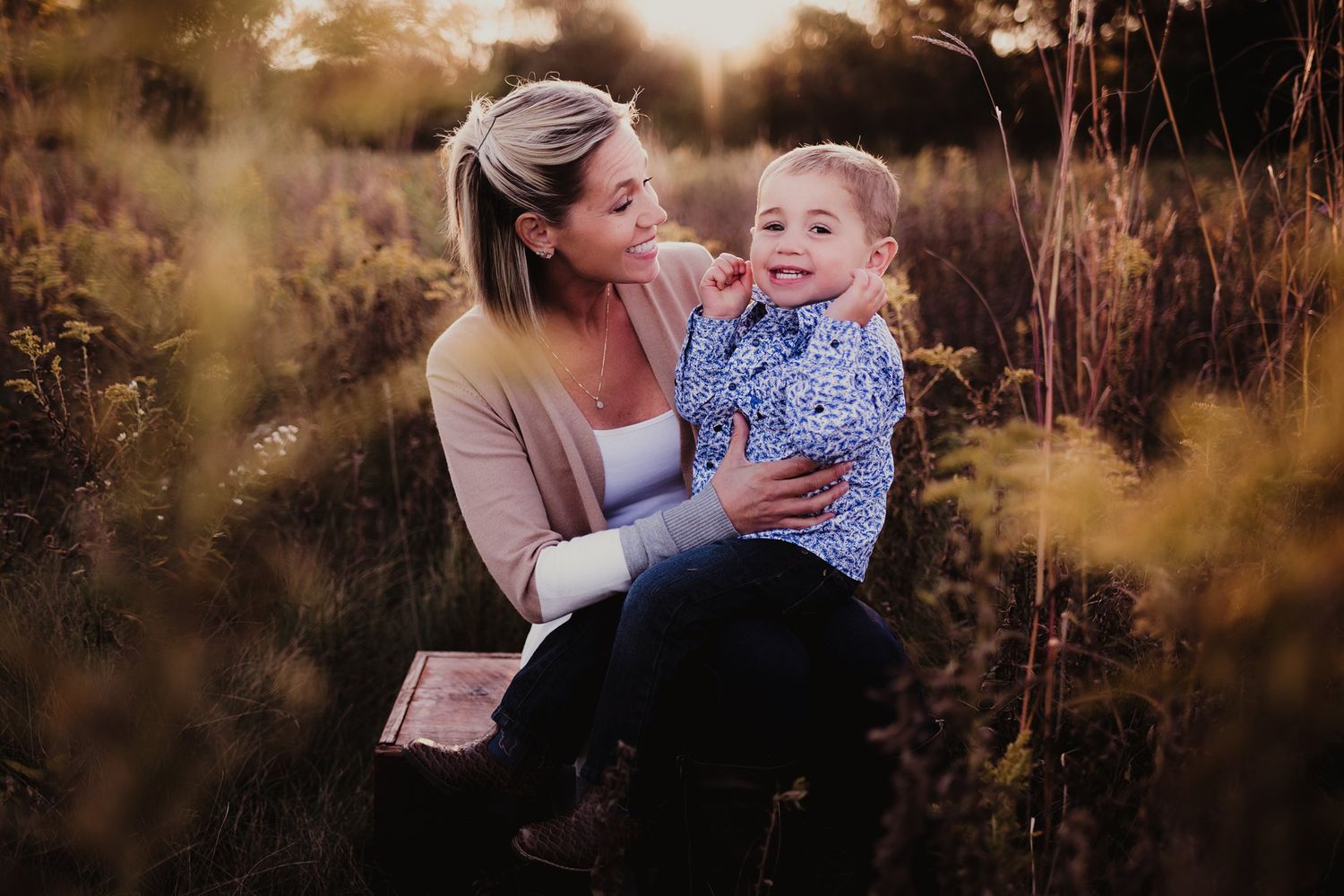 A tender family moment captured in a golden field at sunset.