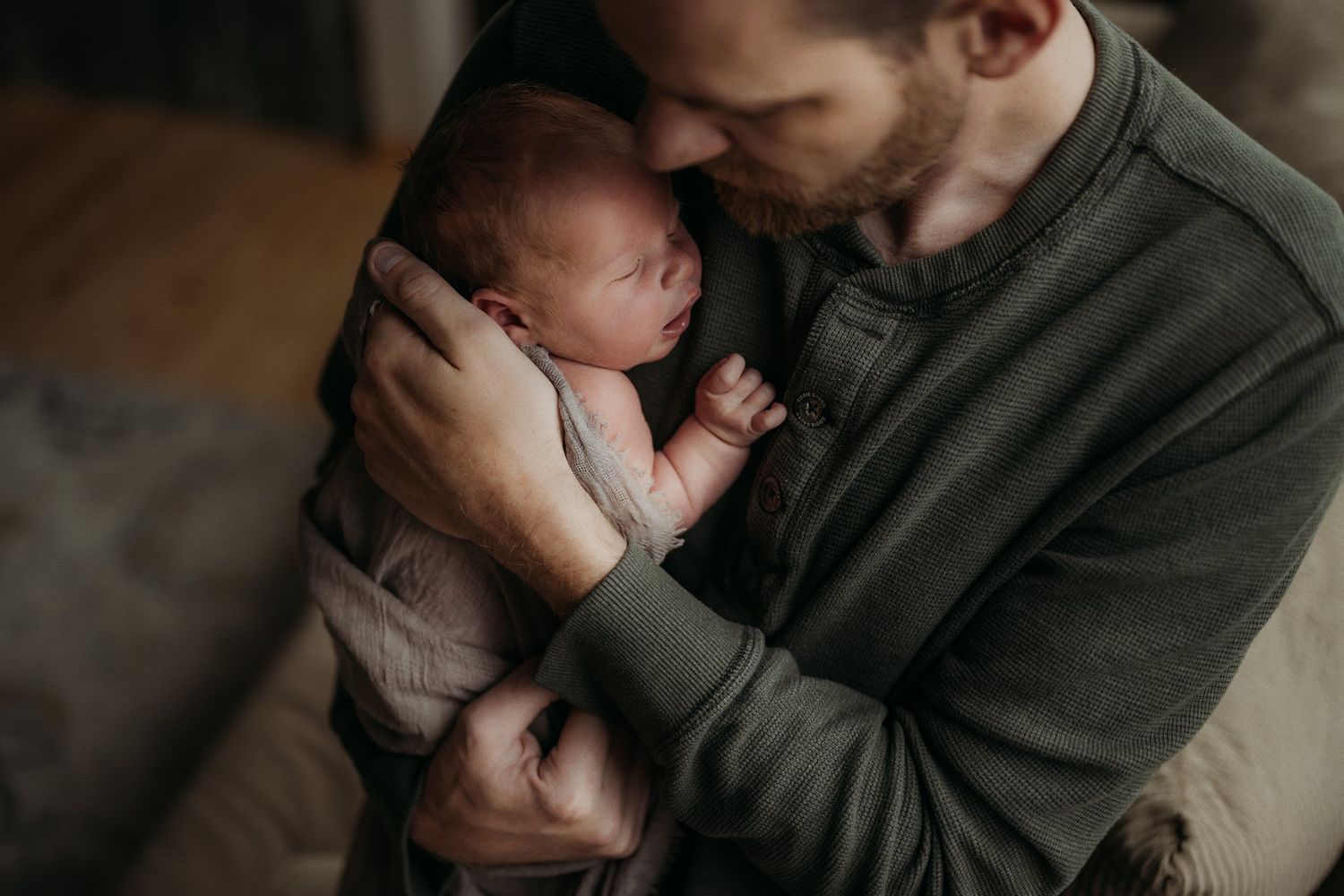 Intimate moment between parent and newborn baby in gray sweater.