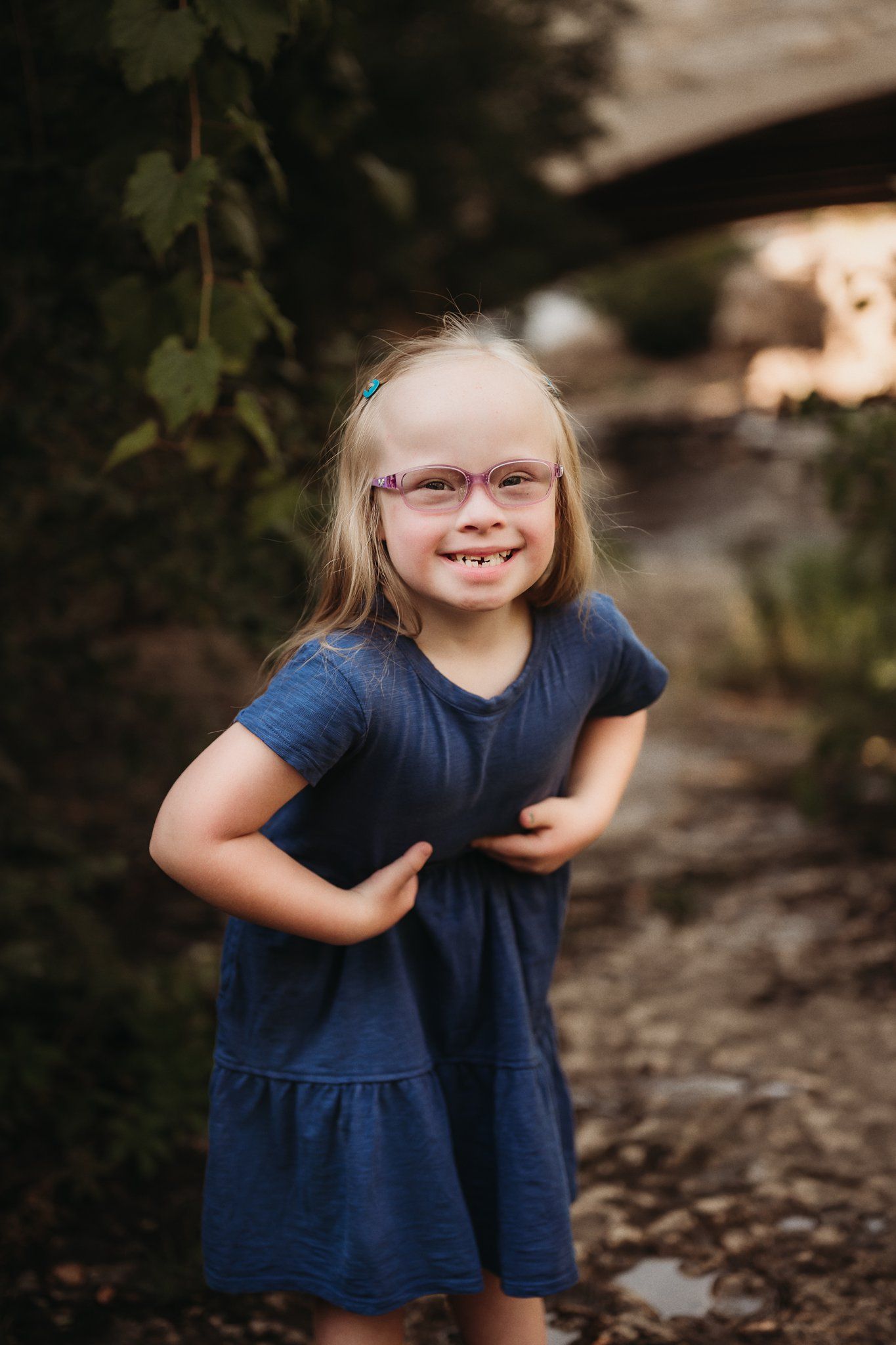 Child in navy blue dress smiling brightly outdoors.