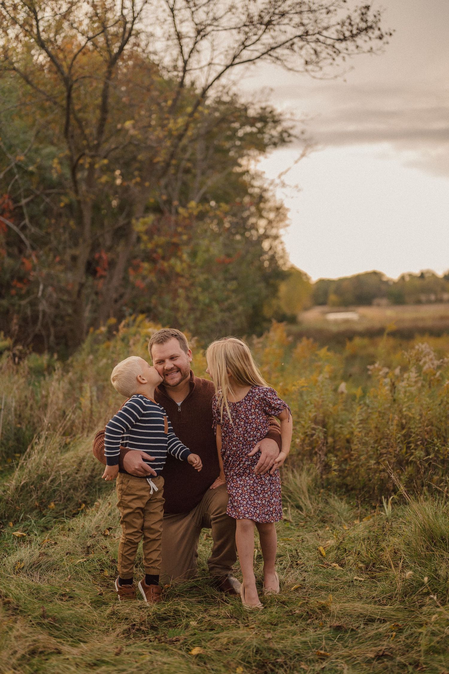Family shares joyful moments together in golden autumn field at sunset.