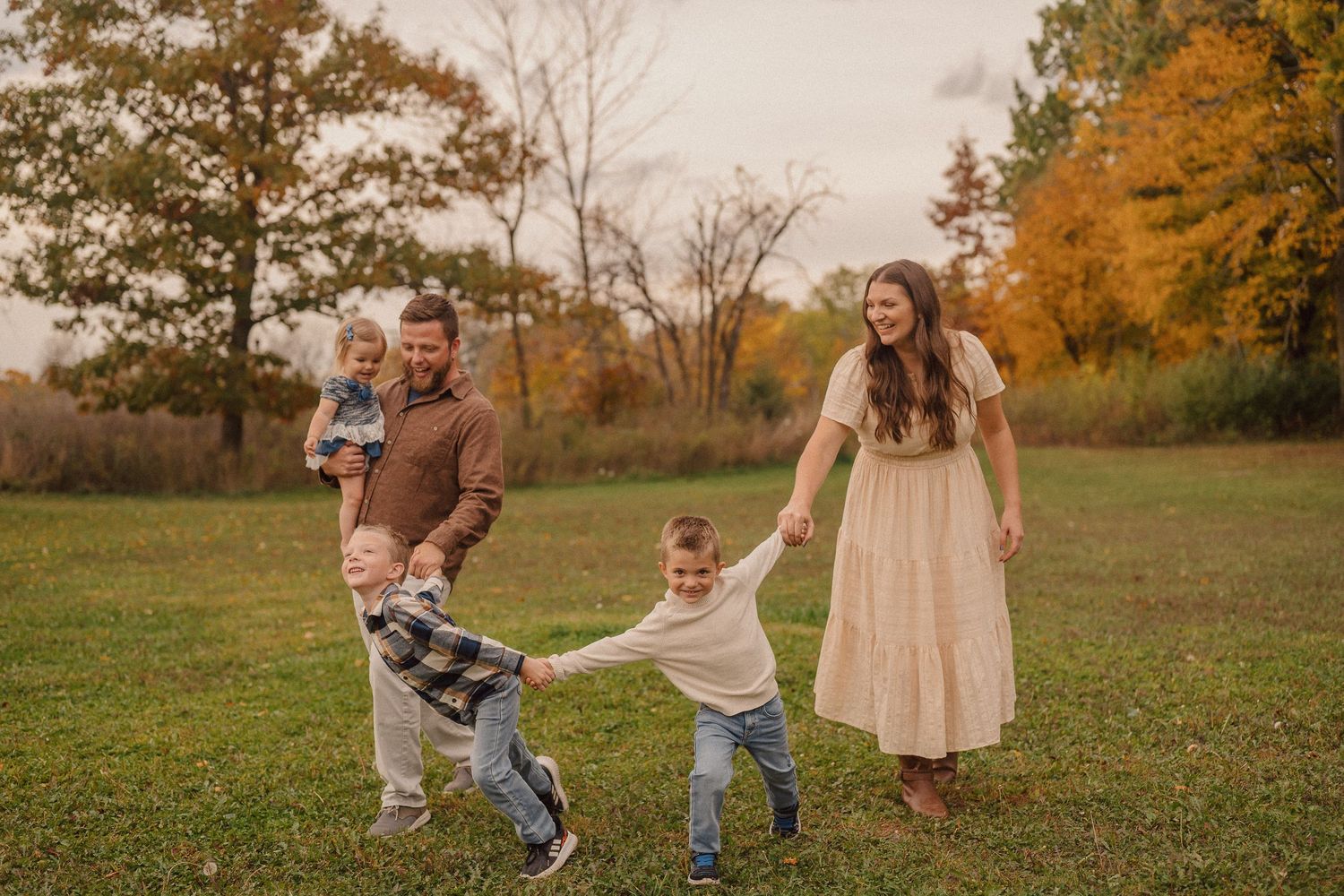 A group enjoying a playful moment together in a grassy field during golden autumn sunset light.