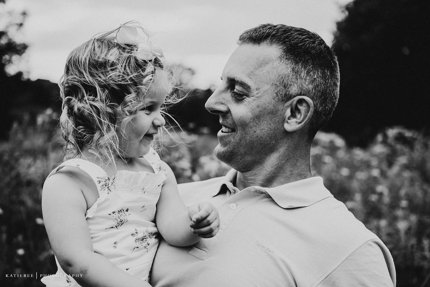 Black and white portrait of joyful parent and child sharing a special moment in a flower field.