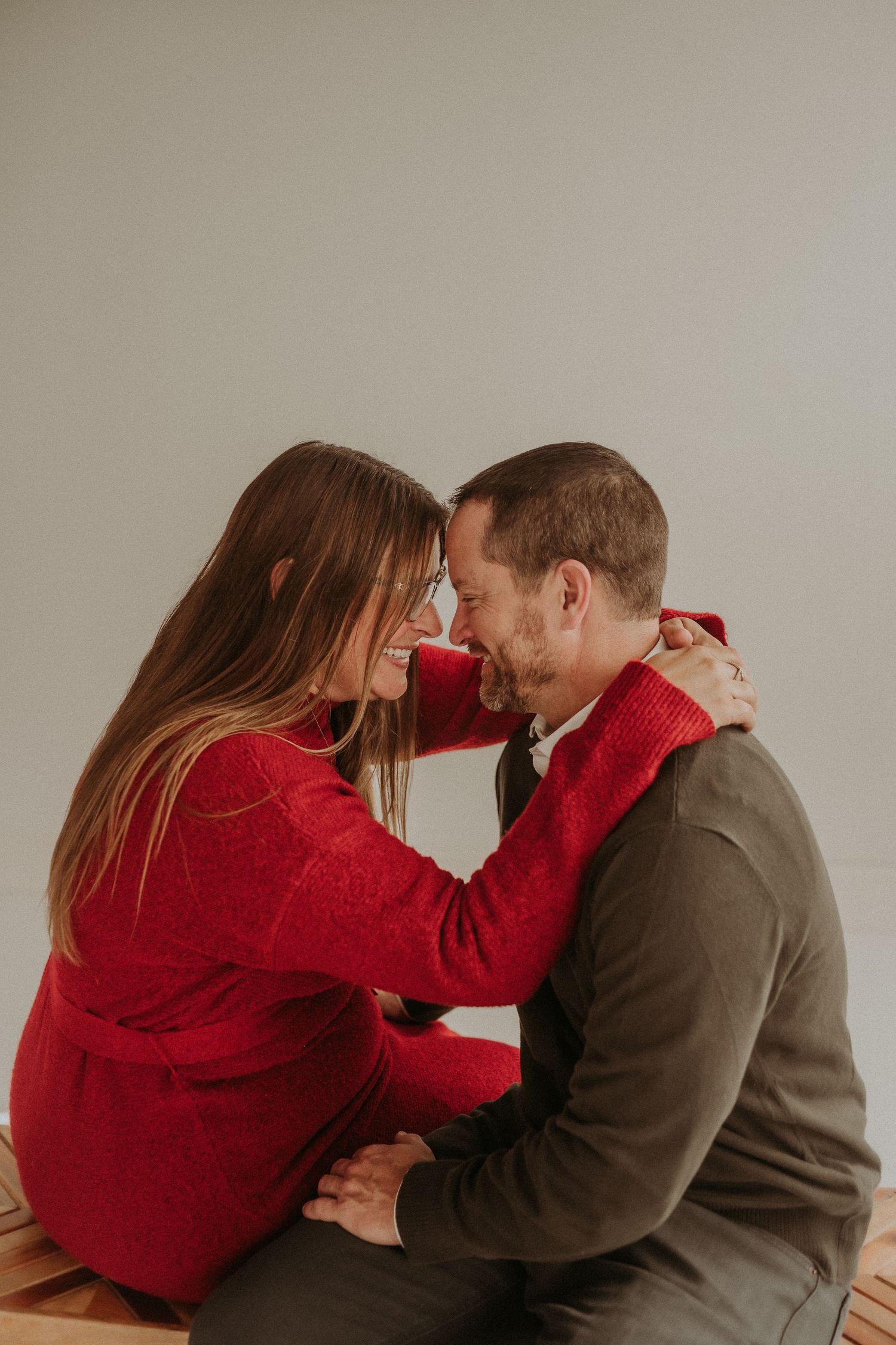 An intimate portrait of a couple in red and brown sweaters sharing a tender moment.