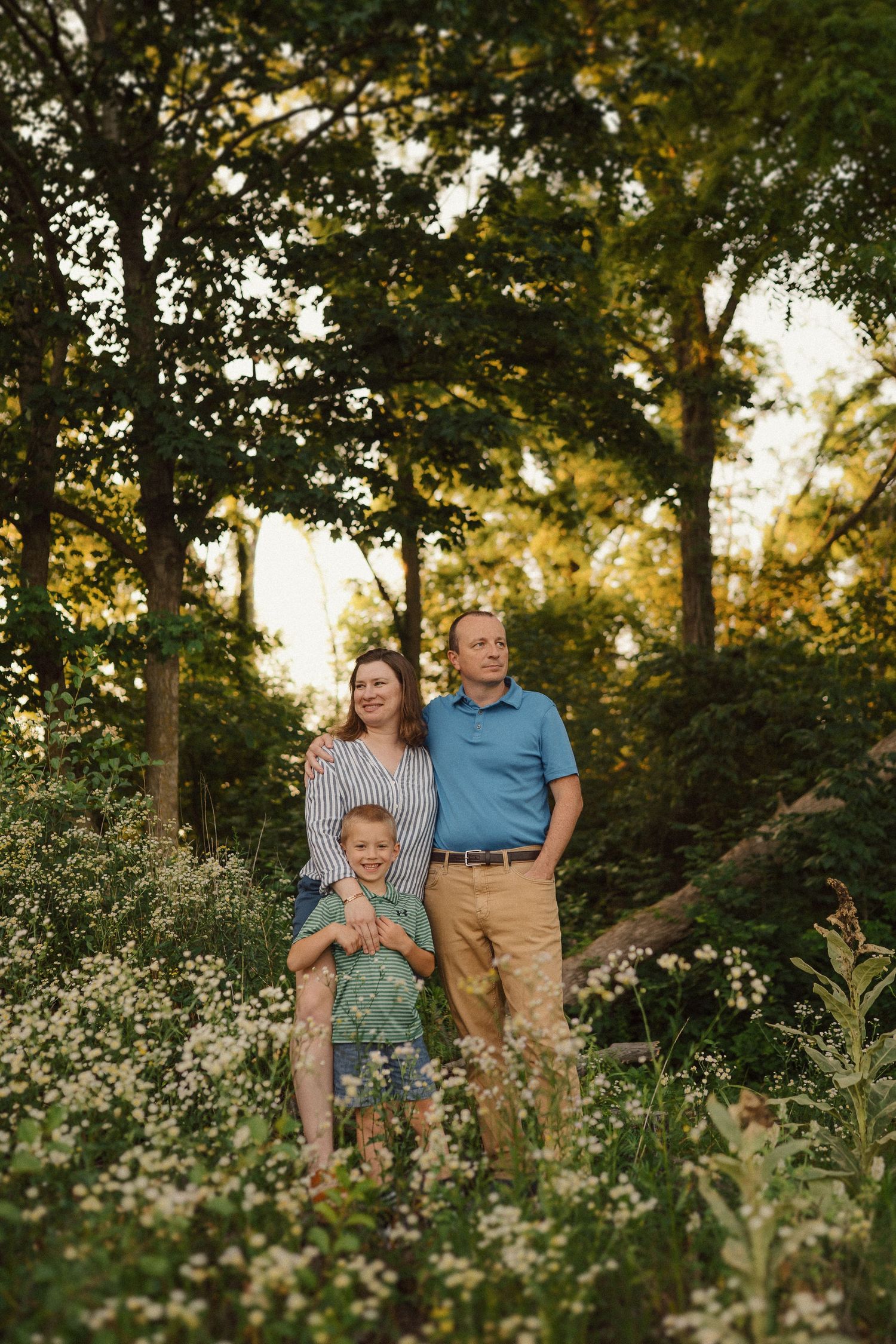 A family portrait taken in a wildflower meadow during golden hour with trees in the background.