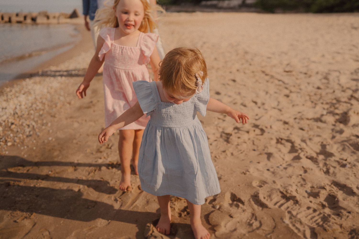 Two children playing together on a sandy beach during golden hour.