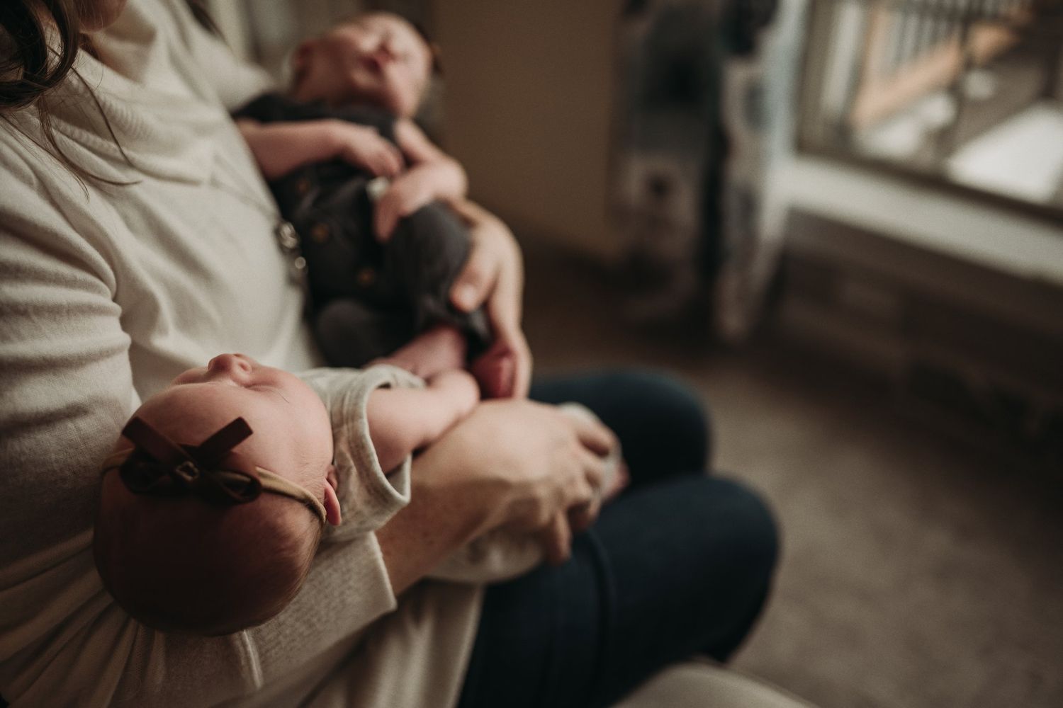 Intimate close-up of parent cradling infant in soft, warm lighting.