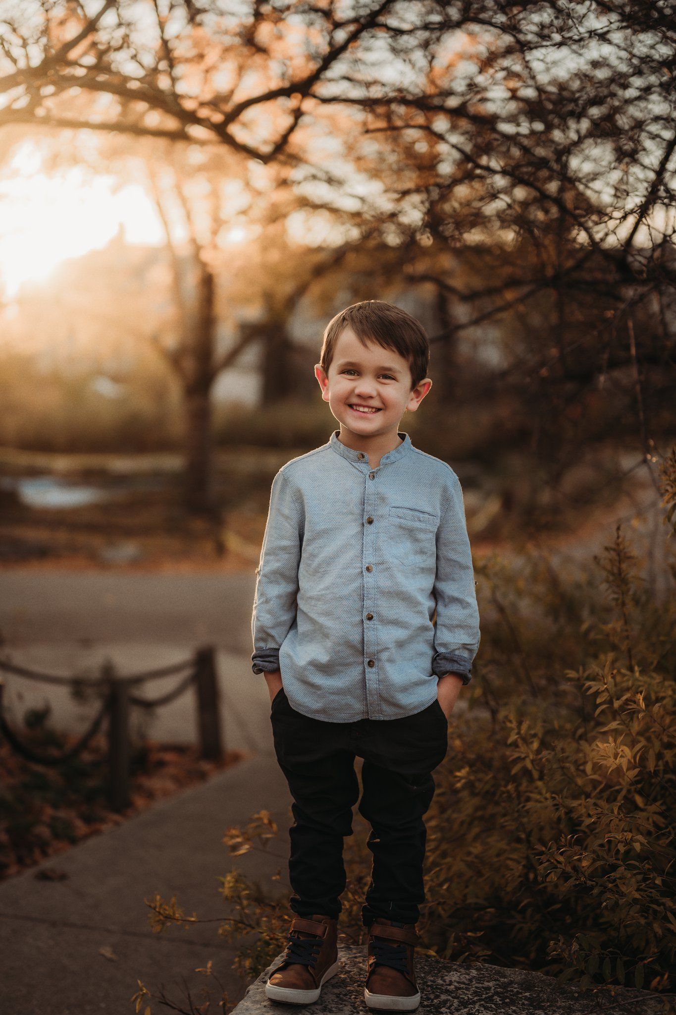 A casual portrait in a light blue button-up shirt during sunset in a park.
