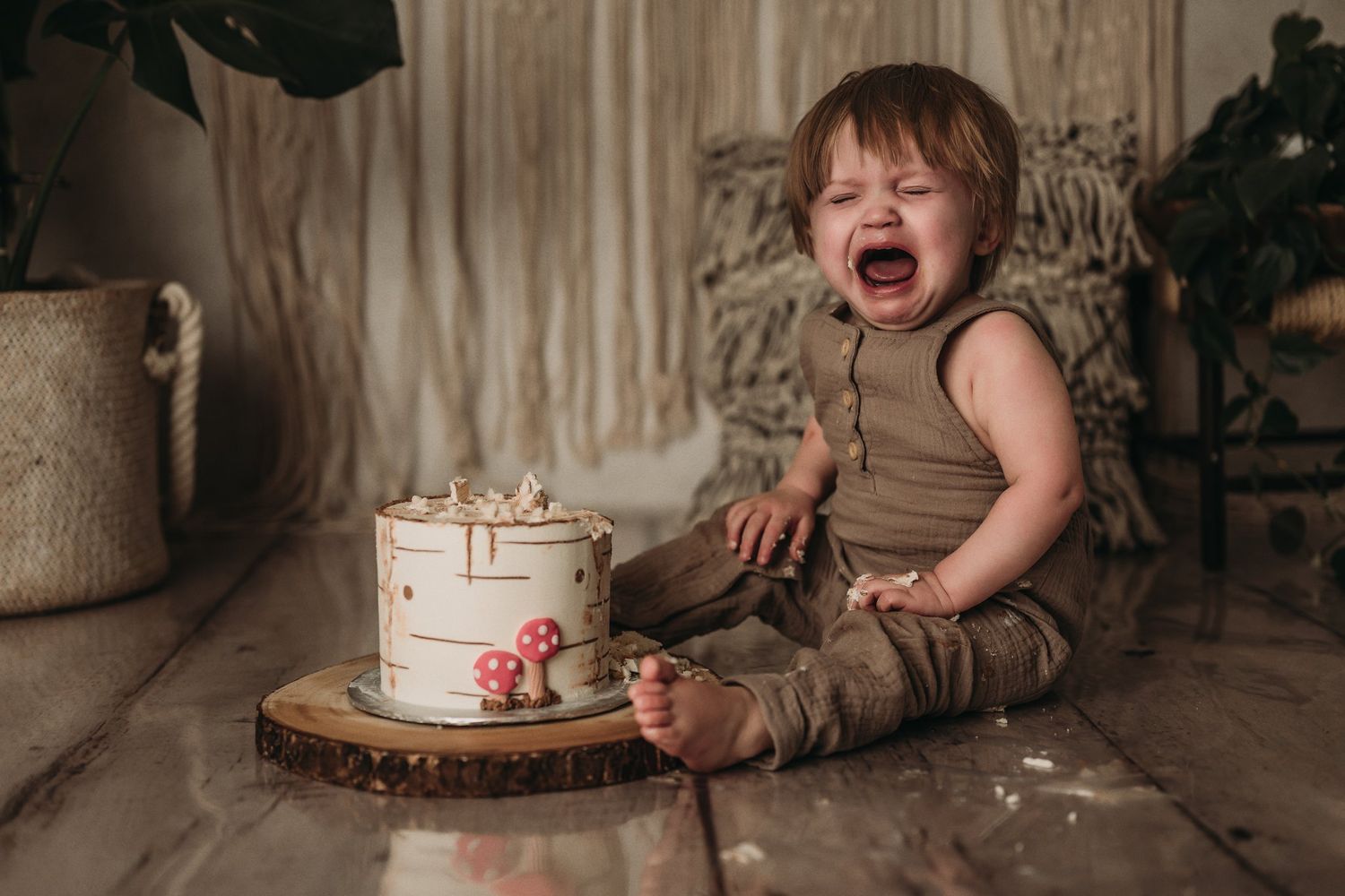 An emotional moment during a woodland-themed cake smash photoshoot with rustic decorations.