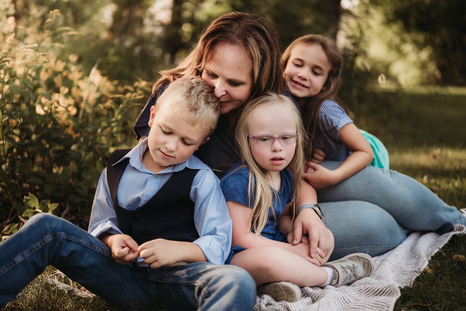 A tender family portrait shows everyone cuddled close together on a picnic blanket.