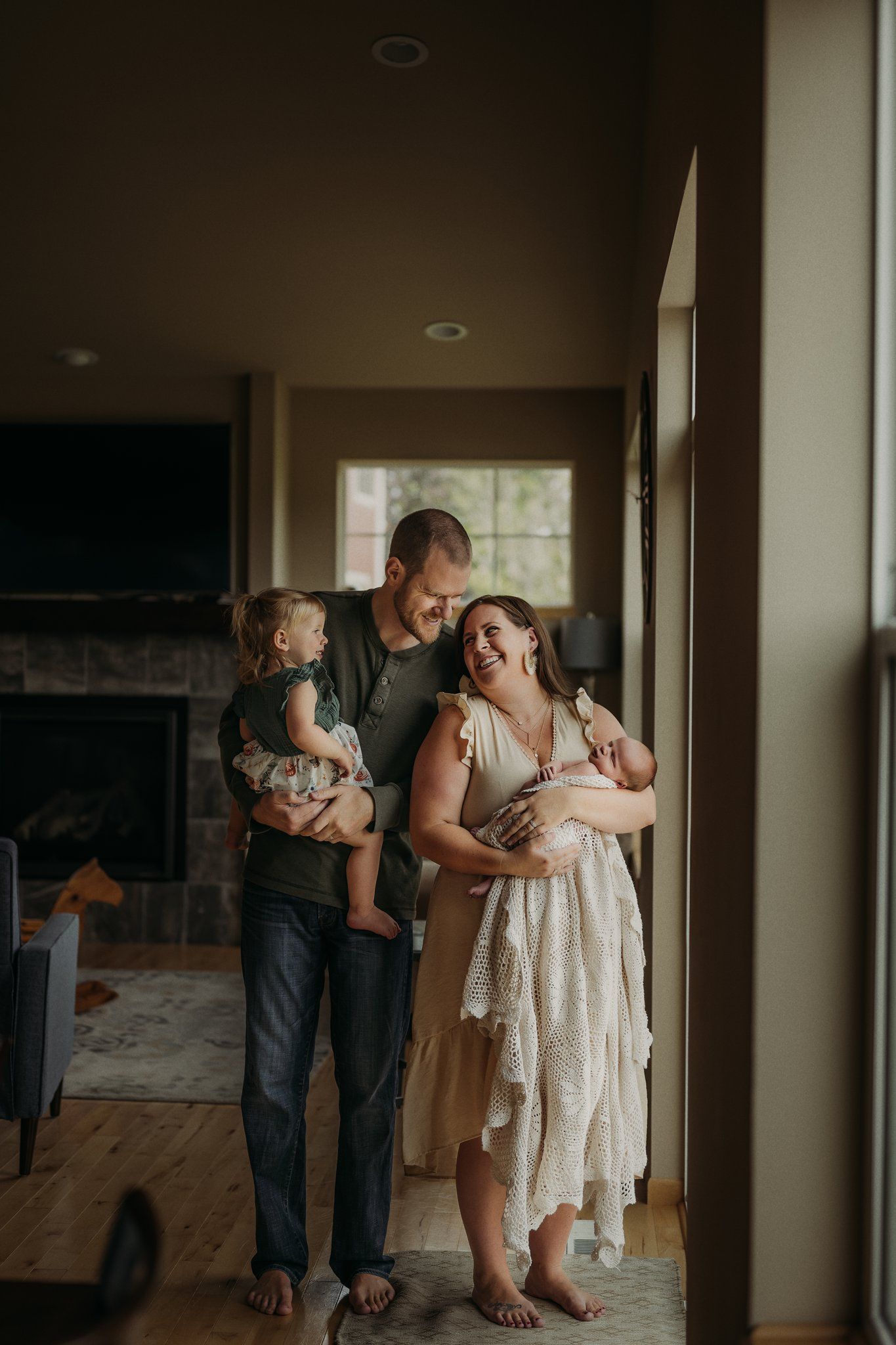 Family of four sharing joyful moment together by window in living room with fireplace.