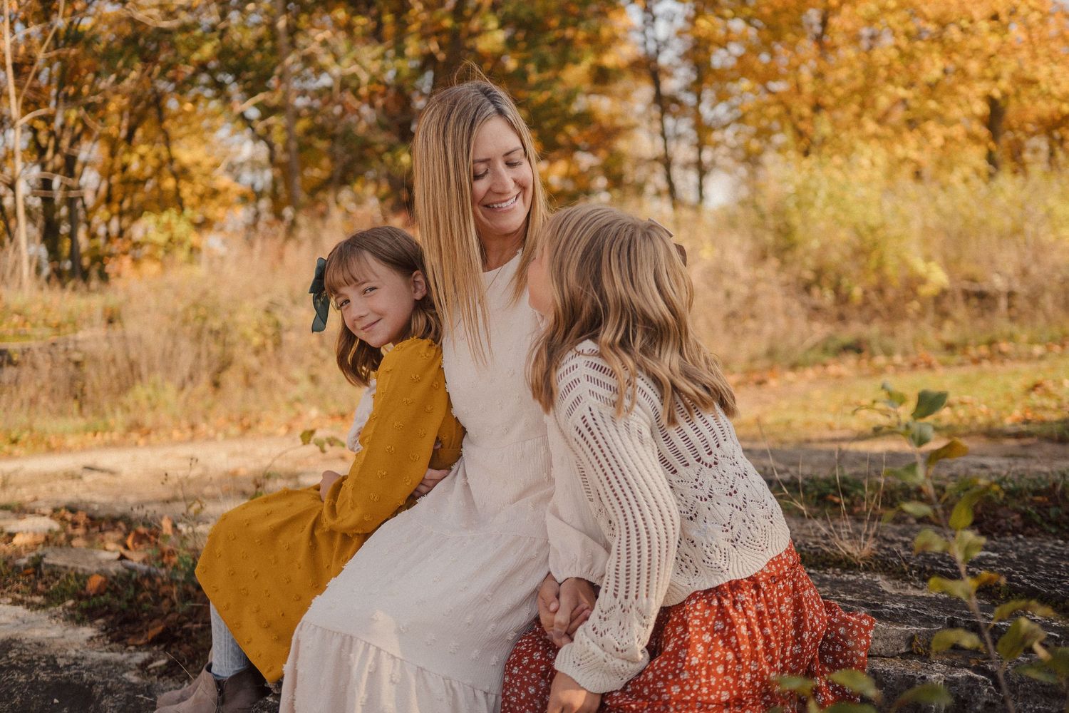 Family enjoying a warm autumn day together outdoors with golden foliage in the background.